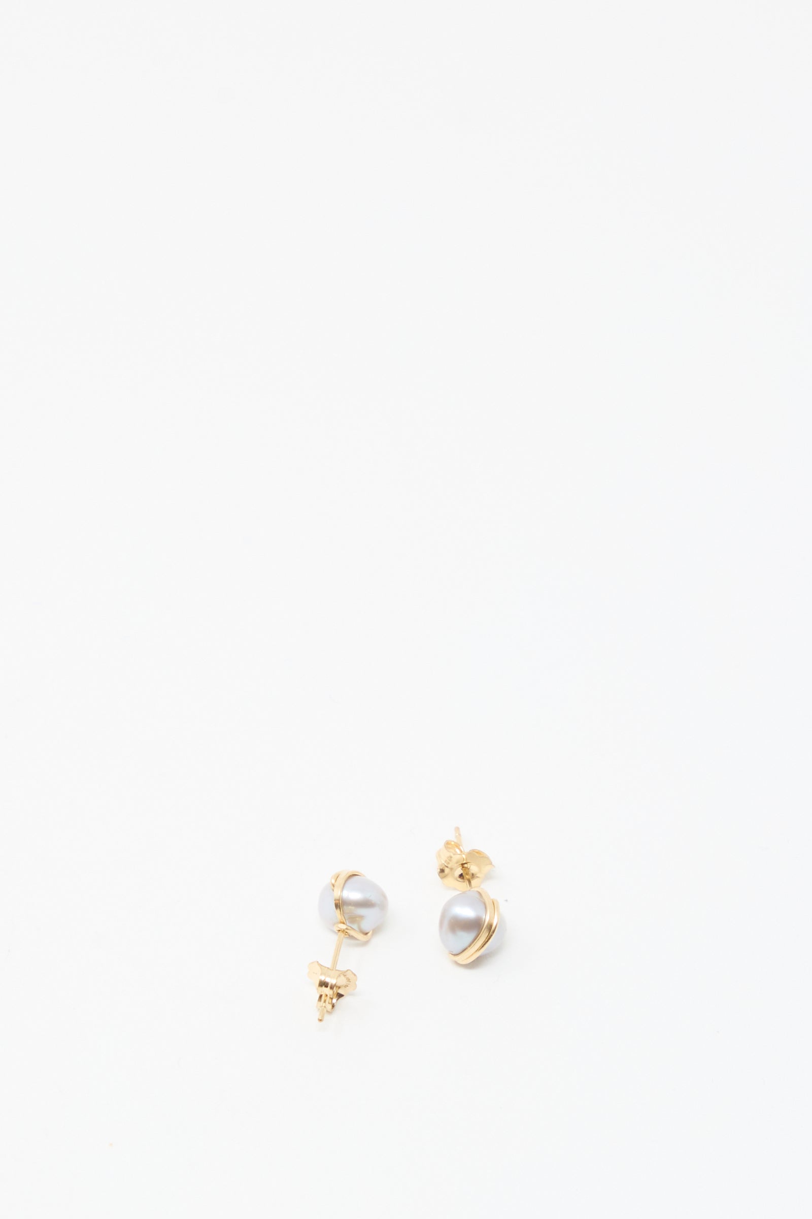 The Baroque Pearl Studs in Silver by Mary MacGill are small silver stud earrings featuring unique baroque pearls, displayed on a plain white background.