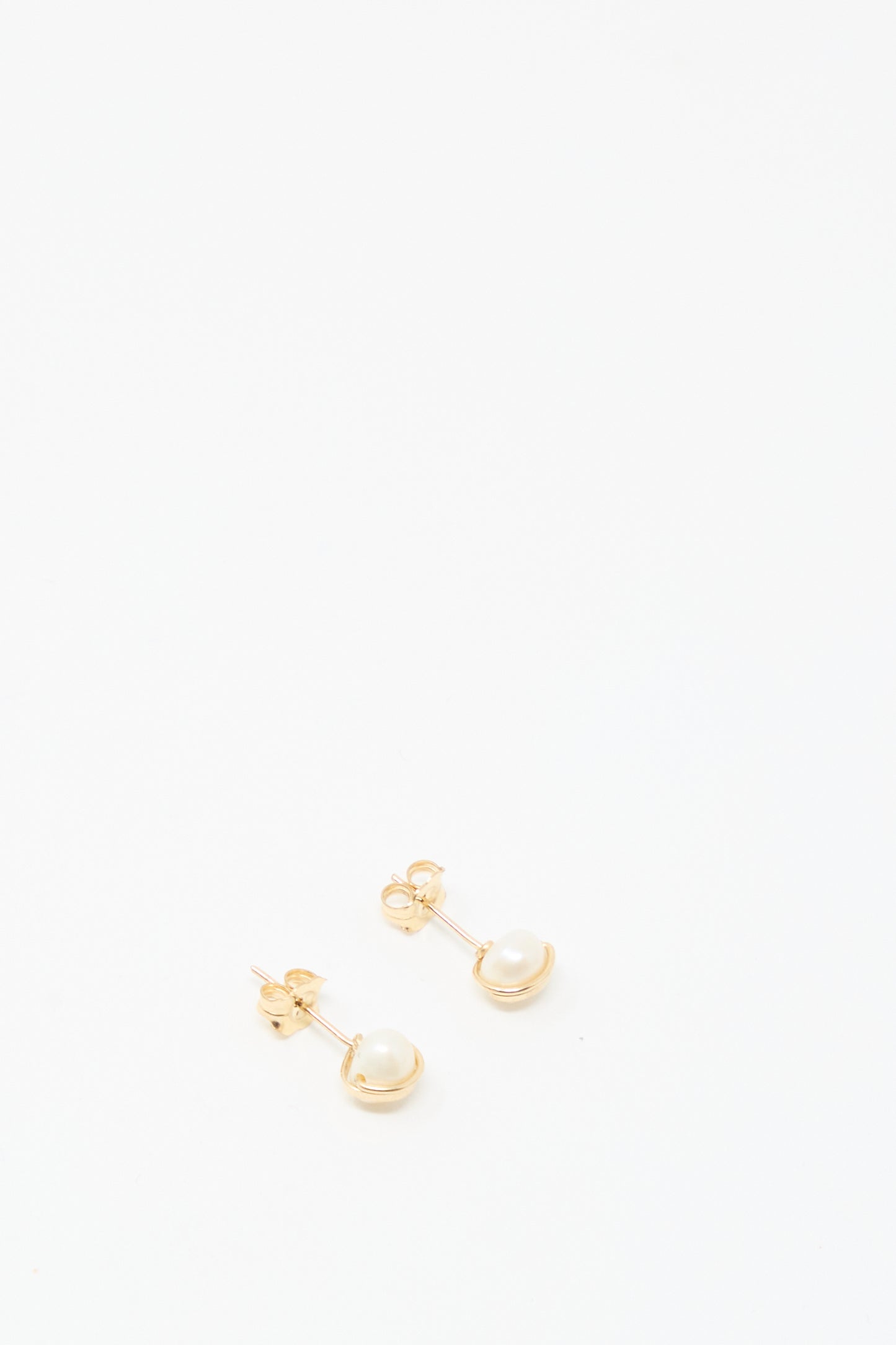 The Baroque Pearl Studs in White by Mary MacGill feature small round white pearls on gold-filled studs, ideal for adding a handmade touch to your collection.