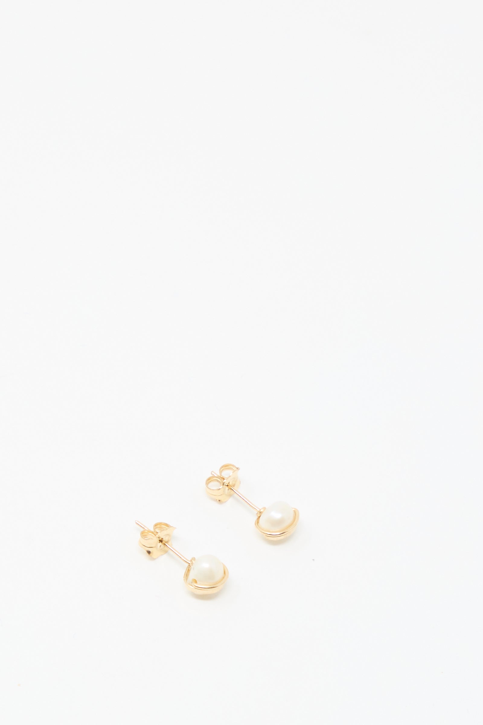 The Baroque Pearl Studs in White by Mary MacGill feature small round white pearls on gold-filled studs, ideal for adding a handmade touch to your collection.