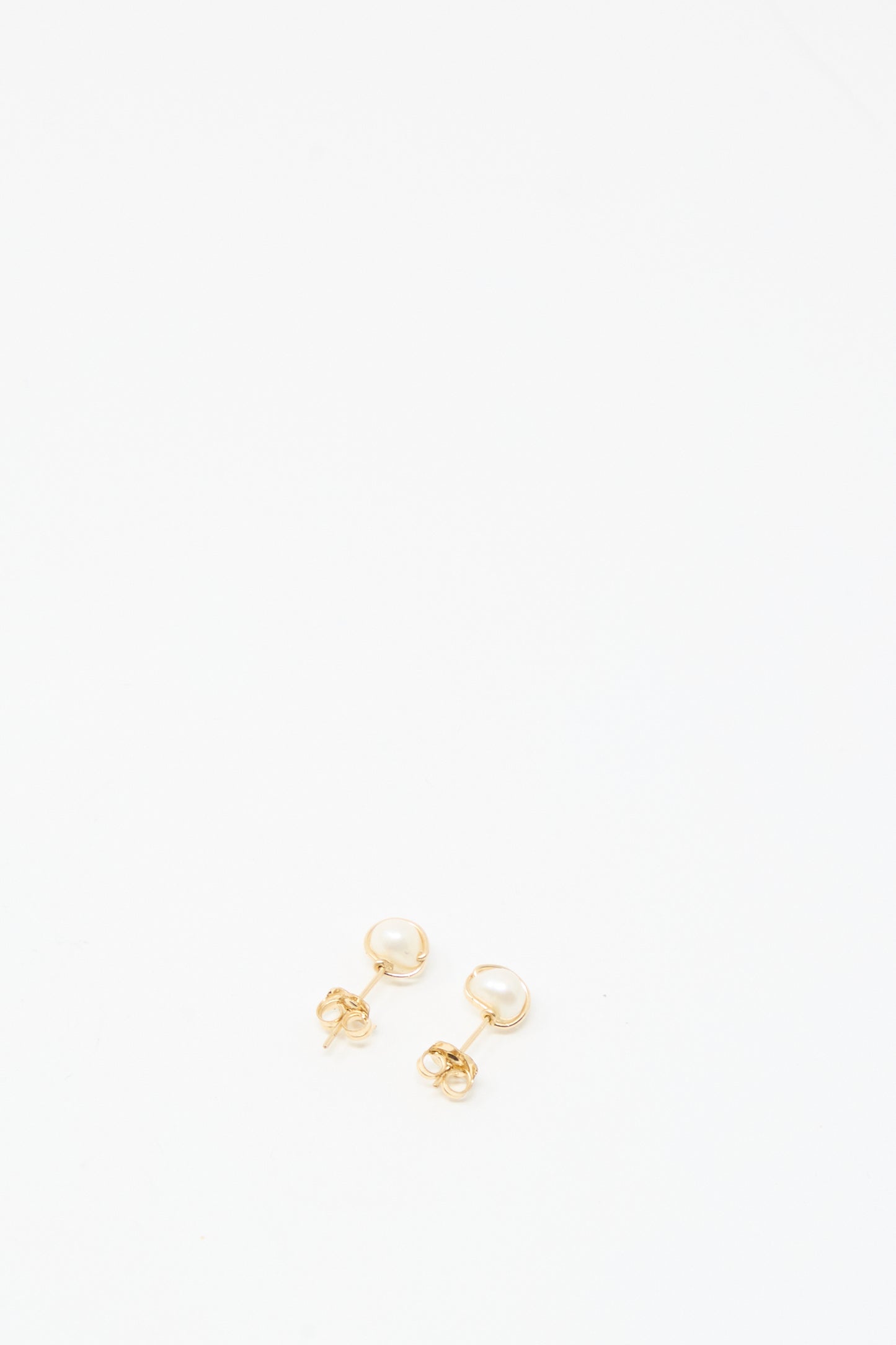 The Baroque Pearl Studs in White by Mary MacGill are small gold-filled stud earrings with round white pearls, shown on a plain white background.