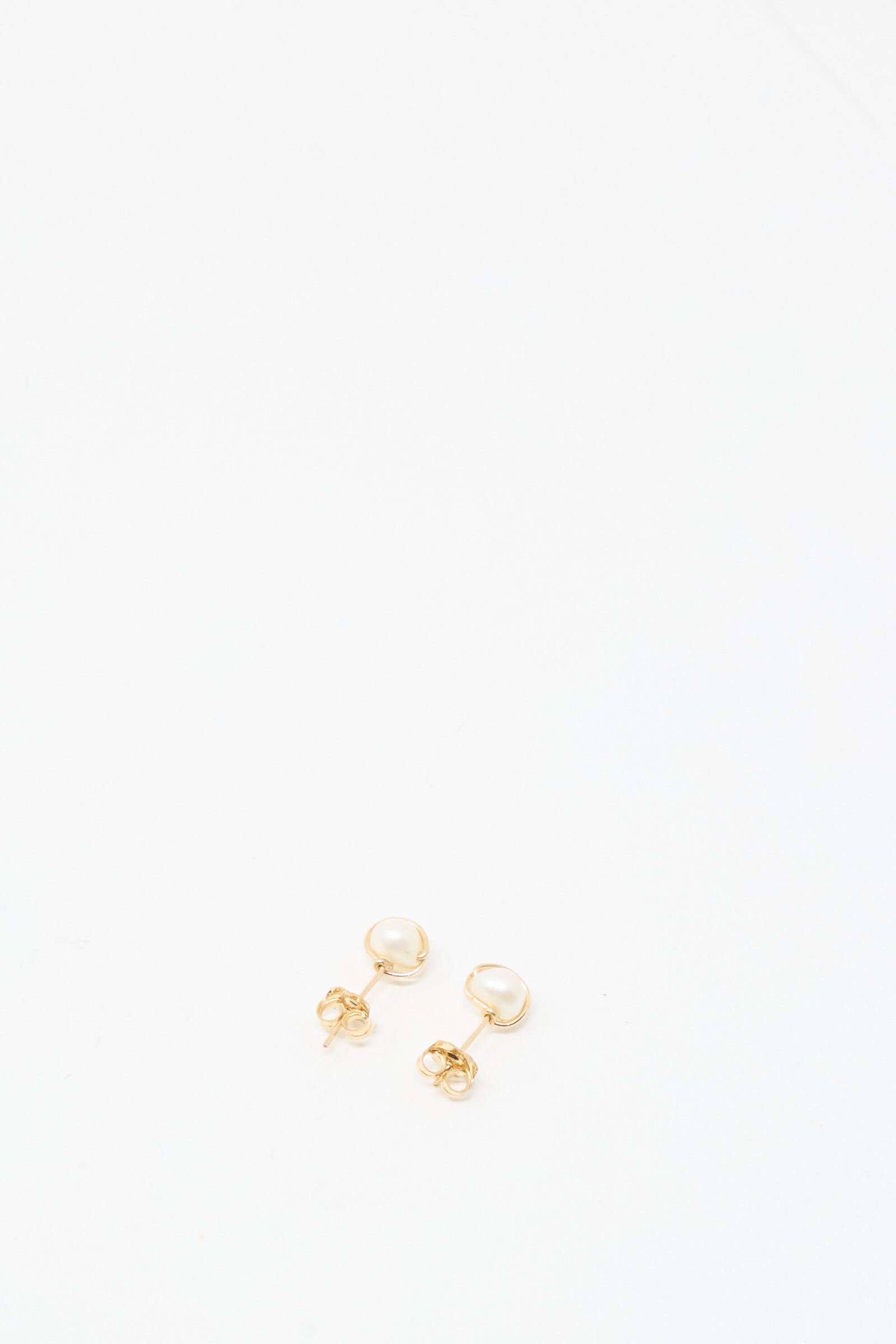 The Baroque Pearl Studs in White by Mary MacGill are small gold-filled stud earrings with round white pearls, shown on a plain white background.