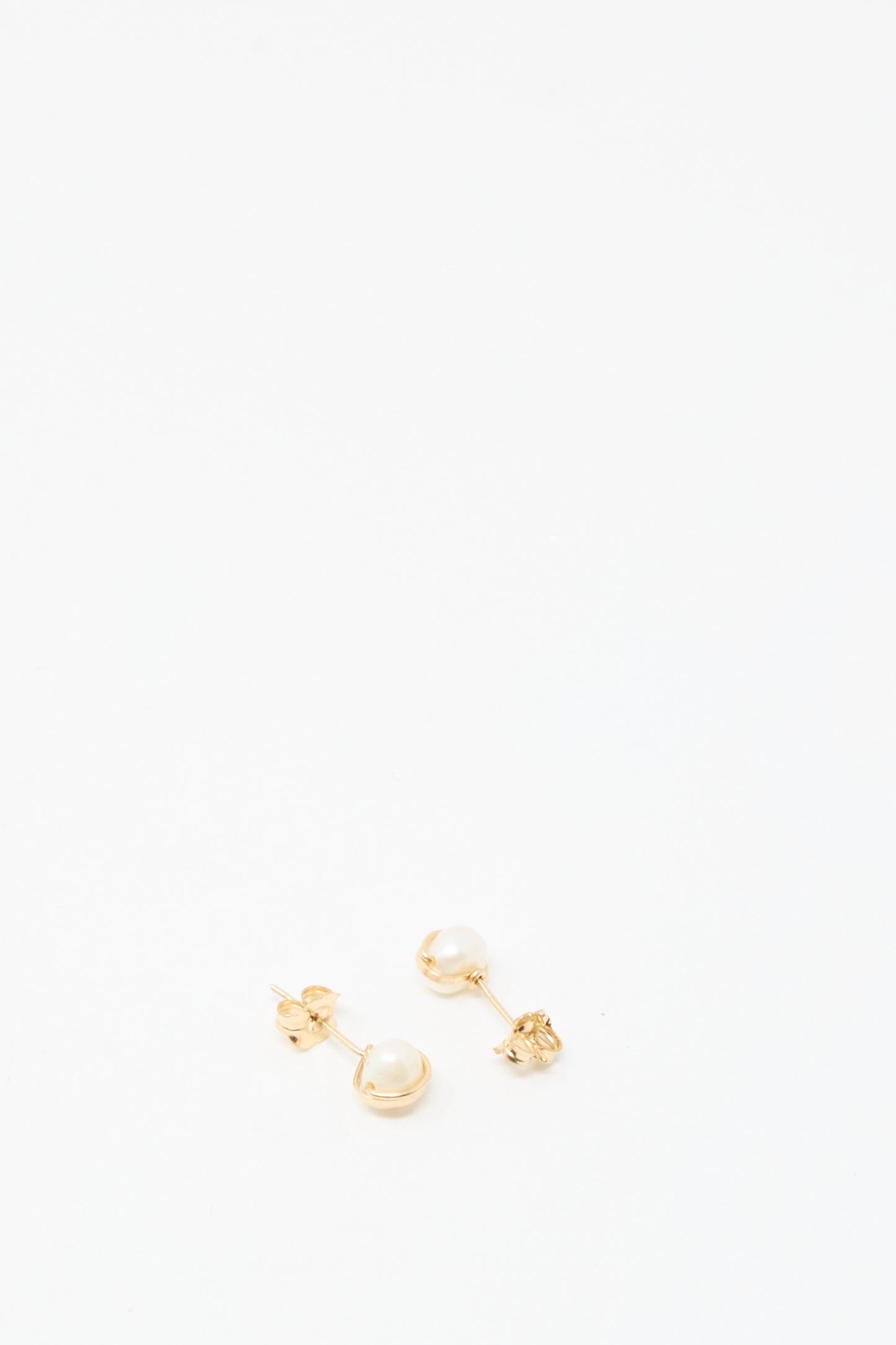 The Baroque Pearl Studs in White by Mary MacGill feature small gold-filled studs with white pearls, elegantly displayed on a plain white background.