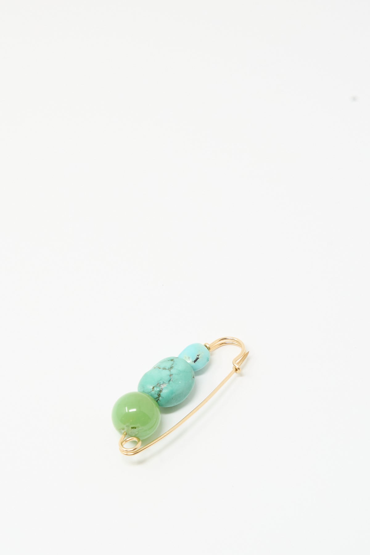 The Chrysoprase and Turquoise Pin by Mary MacGill features gold with two turquoise beads and one green bead, glowing against a white background.