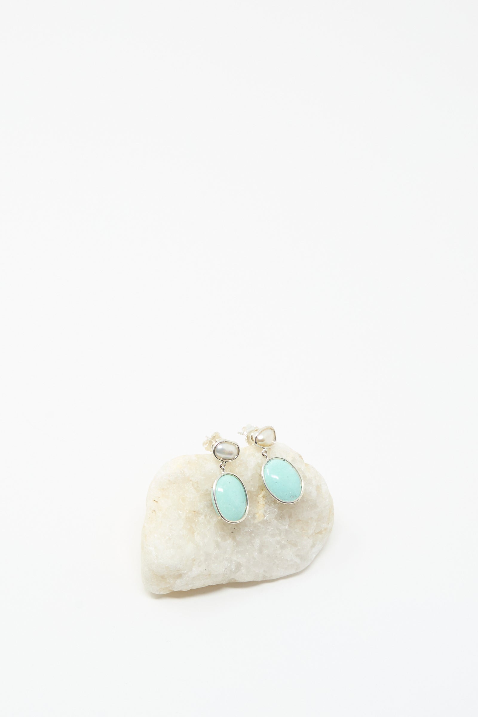 Double Stone Drop Earrings in Keshi Pearl and Turquoise by Mary MacGill, featuring oval turquoise stones set in silver, displayed on a white stone background—ideal for lovers of unique, handmade jewelry.