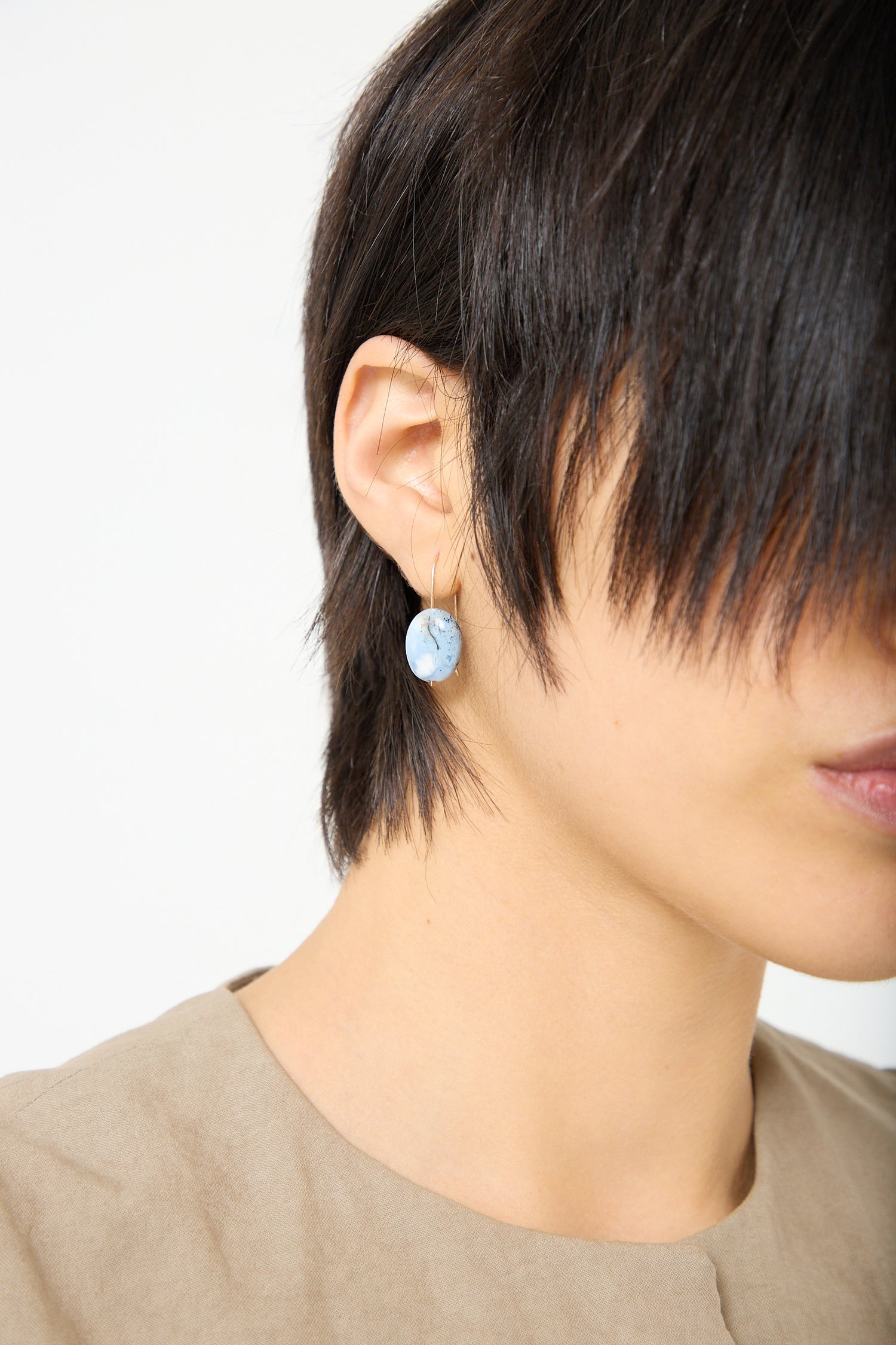 A woman wearing a pair of Mary MacGill drop earrings in Textured Blue Opal.