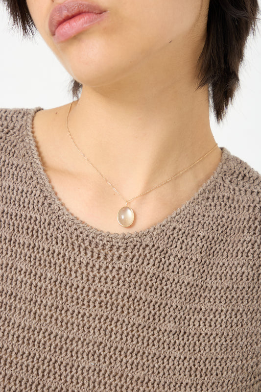 A woman wearing a brown sweater and a Mary MacGill 14K Floating Necklace in Ceylon Moonstone.