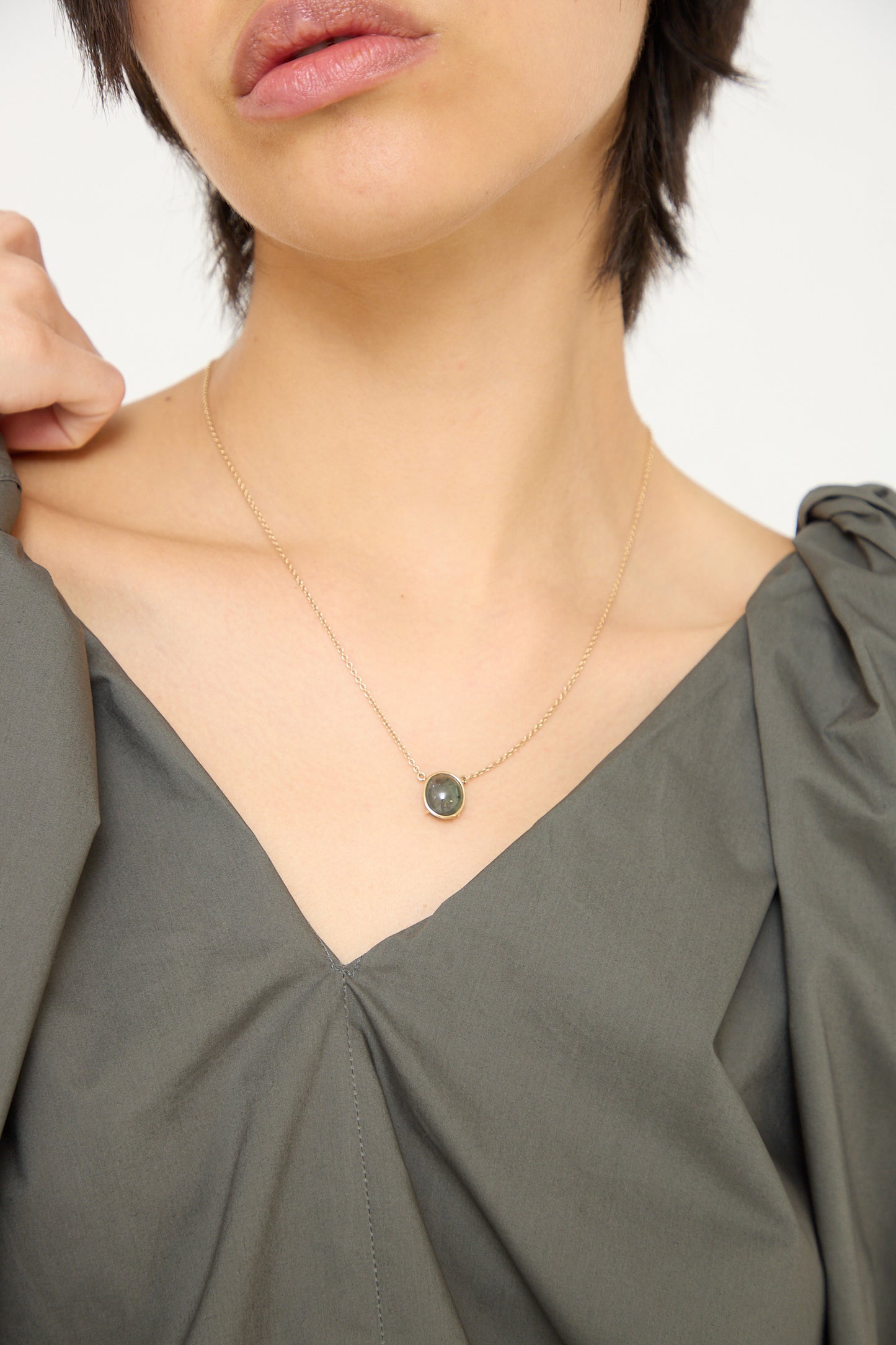 A woman wearing a Mary MacGill Floating Necklace in Light Green Tourmaline with a black stone.