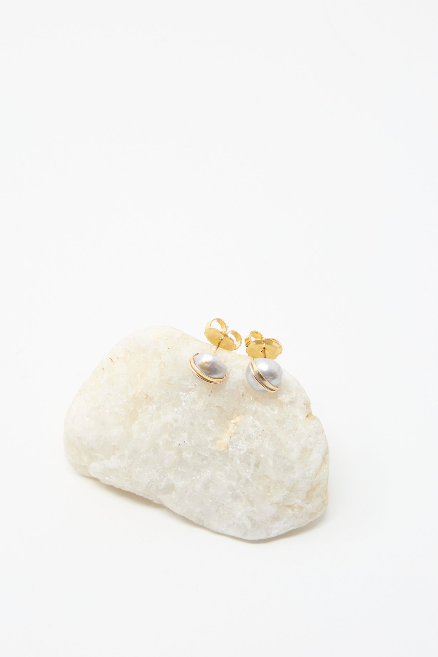 Mary MacGill Grande Baroque Pearl Studs in Silver, handcrafted with lustrous baroque pearls and silver posts, showcased on a white stone against a plain white background.