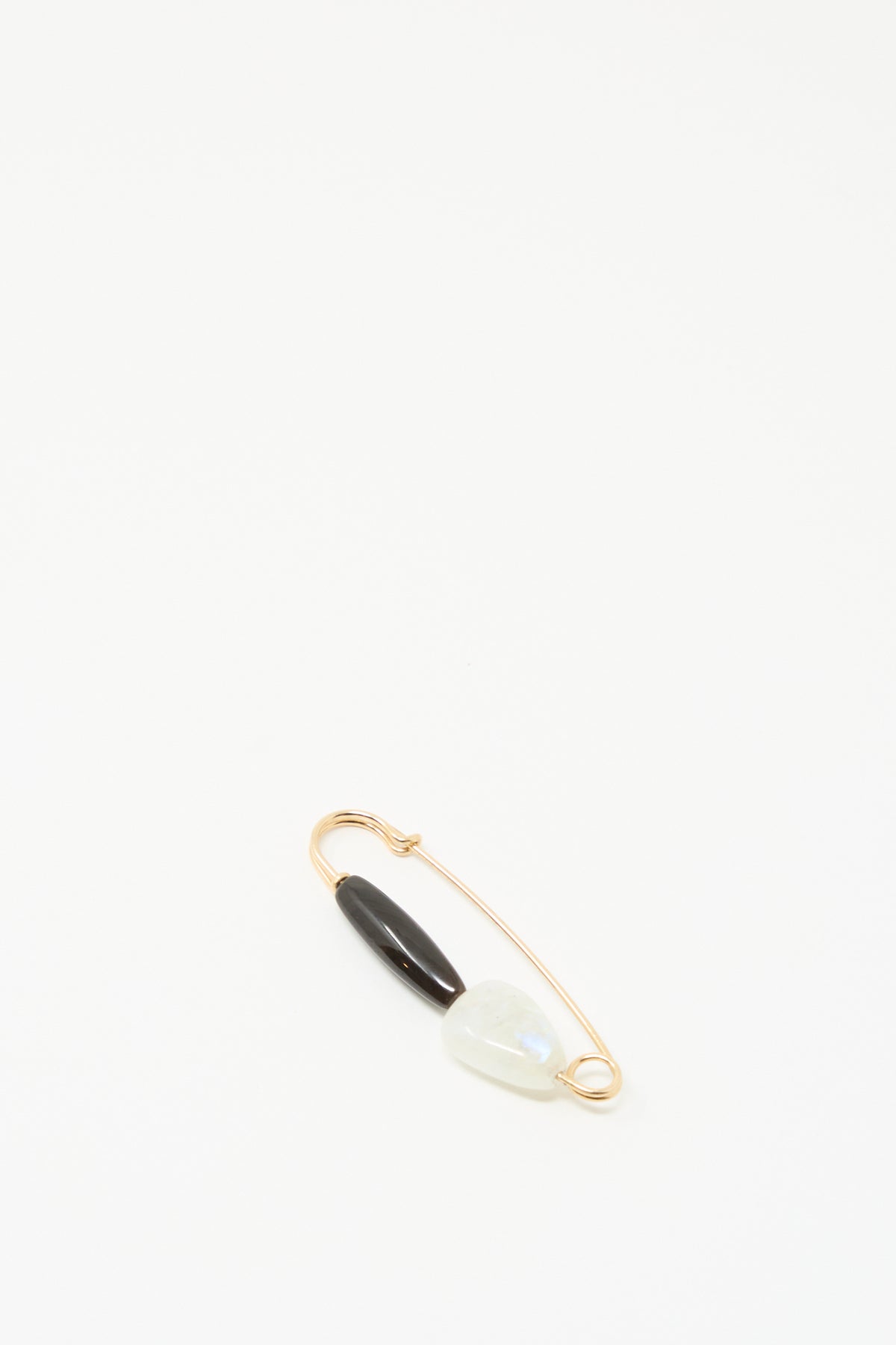 The Moonstone and Agate Pin by Mary MacGill features a gold-filled wire, a black agate bead, and a light moonstone on a plain white background.