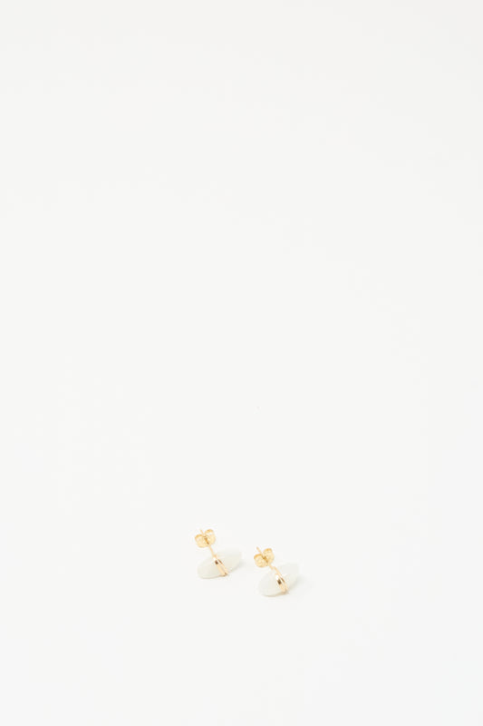 A pair of small gold stud earrings with white oval moonstones, photographed on a seamless white background.