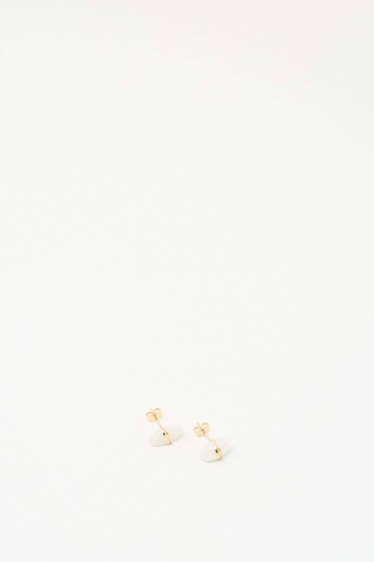 A pair of small gold stud earrings with white oval moonstones, photographed on a clean white background.