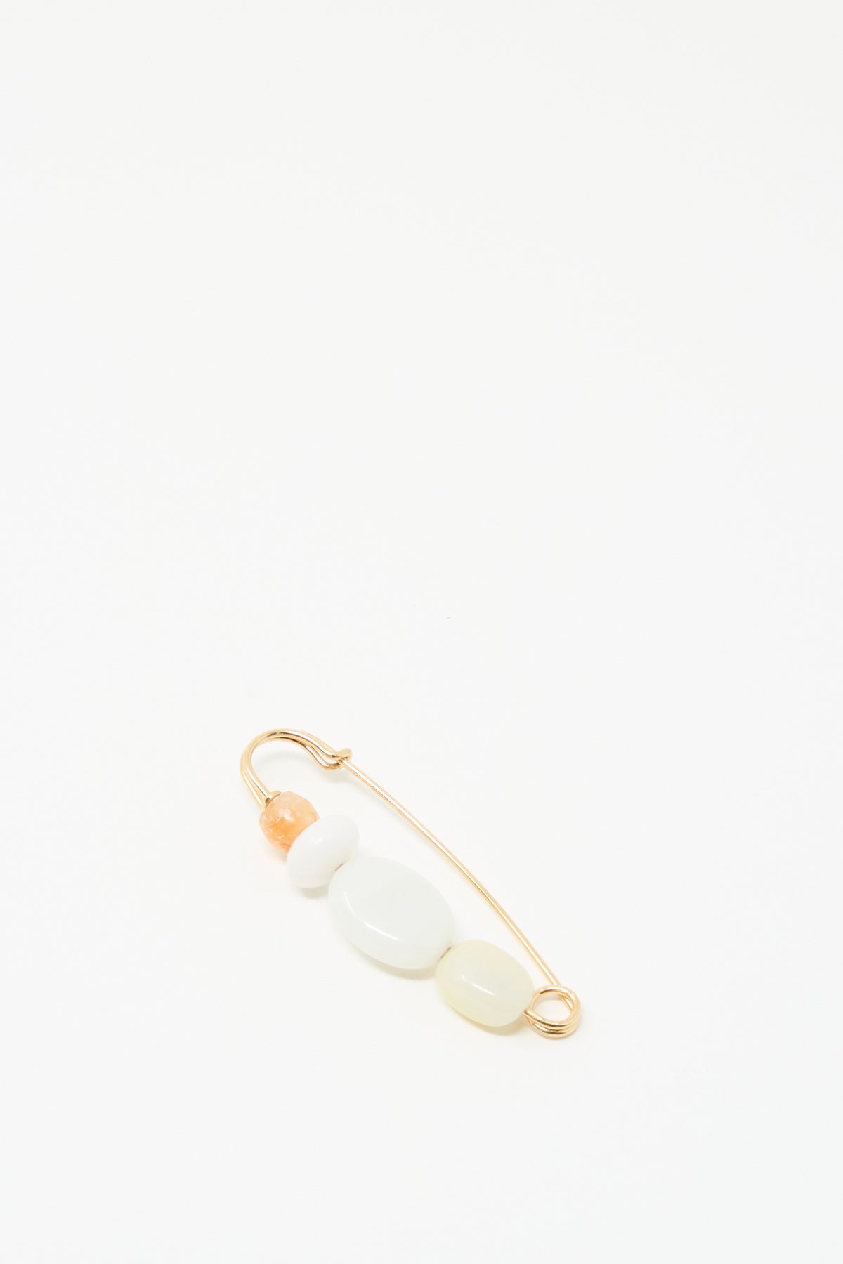 The Mary MacGill Newsprint Pin features a gold-filled wire and four beads—peach, white, and two pale yellow—displayed on a white background.