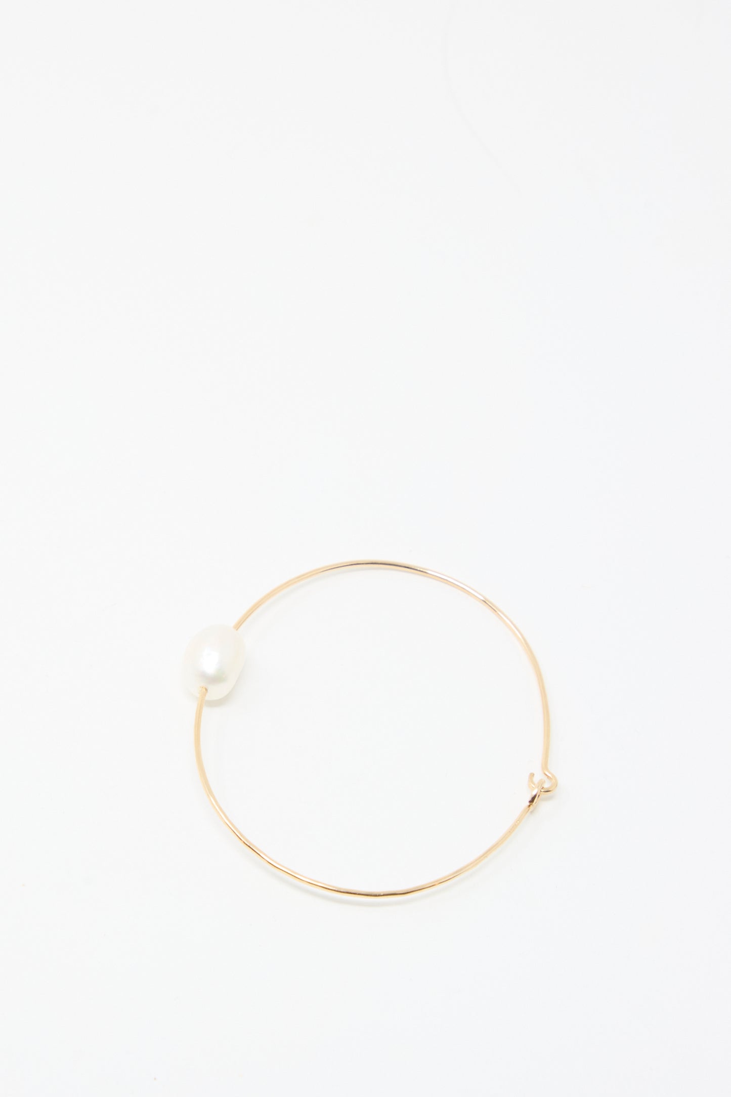 The Mary MacGill Petite Baroque Pearl Cuff in White is a slim gold-filled bracelet adorned with a single white pearl, shown on a plain white background.