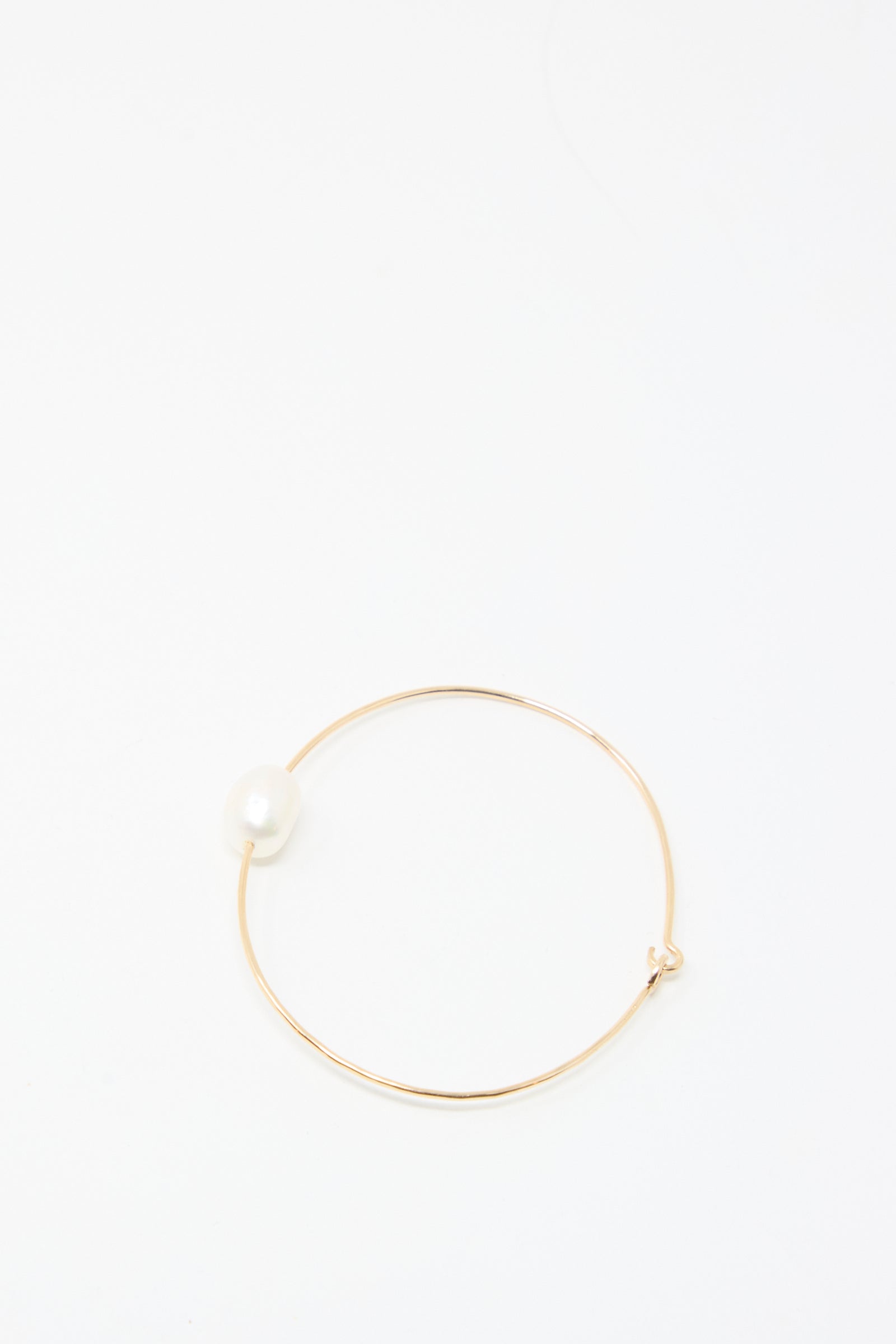 The Mary MacGill Petite Baroque Pearl Cuff in White is a slim gold-filled bracelet adorned with a single white pearl, shown on a plain white background.