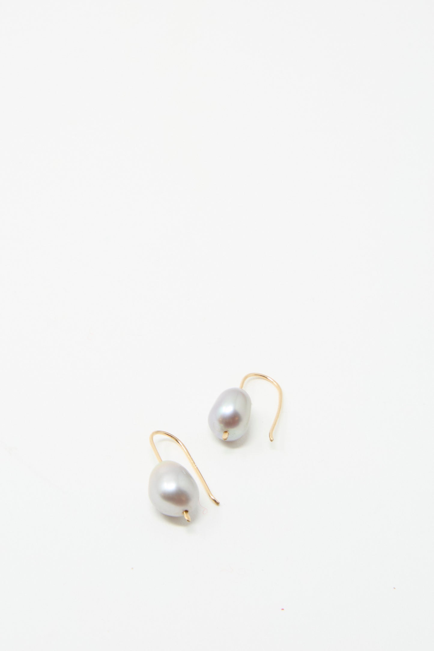 The Petite Baroque Pearl Drop Earrings in Silver by Mary MacGill feature exquisite Baroque pearls elegantly presented on luxurious gold hooks crafted from hammered gold-filled wire against a pristine white background.