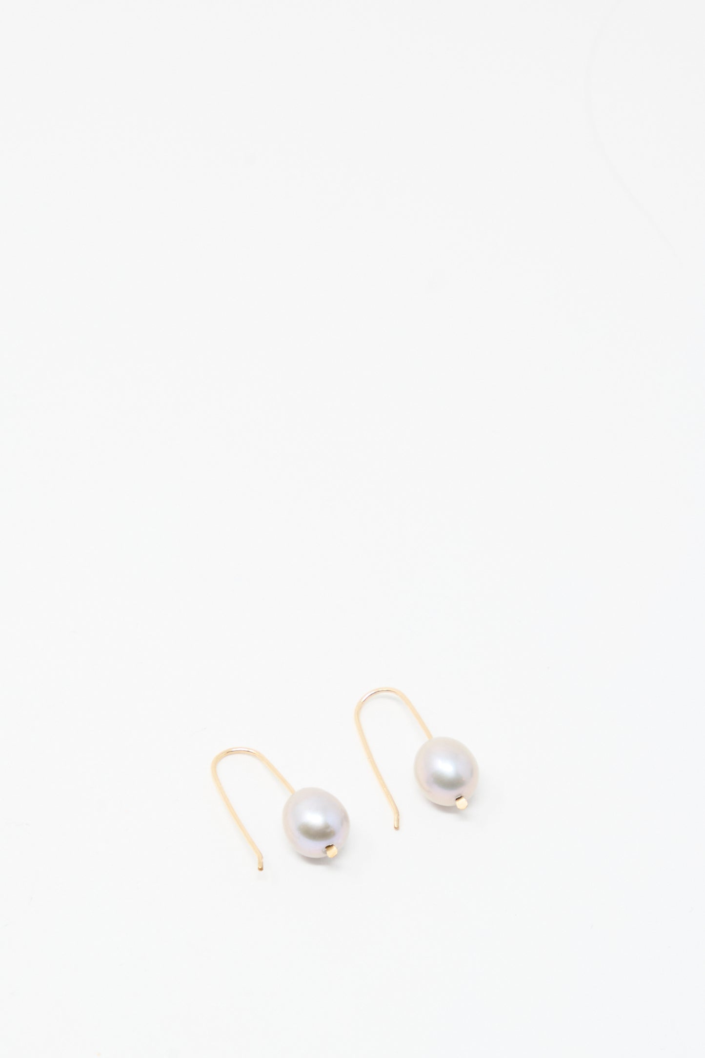 A pair of Mary MacGill Petite Baroque Pearl Drop Earrings in Silver, each showcasing a single baroque pearl, displayed on a plain white background.