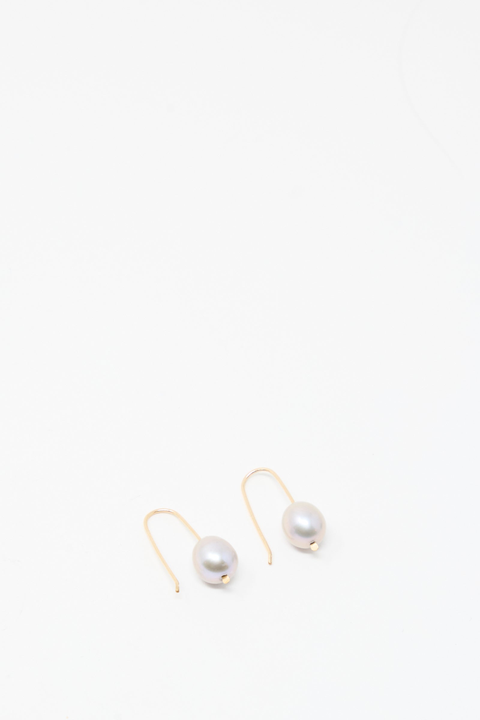 A pair of Mary MacGill Petite Baroque Pearl Drop Earrings in Silver, each showcasing a single baroque pearl, displayed on a plain white background.