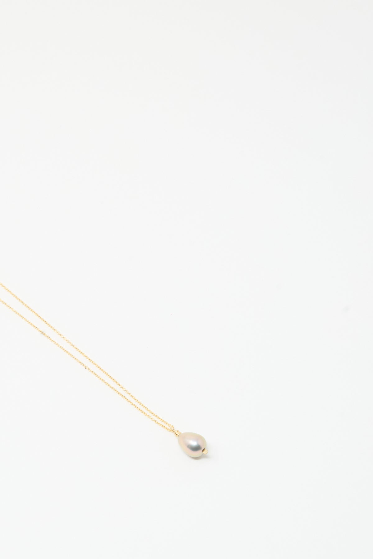 The Petite Baroque Pearl Drop Necklace 18″ in Silver by Mary MacGill features a single baroque pearl pendant on a delicate chain against a plain white background.