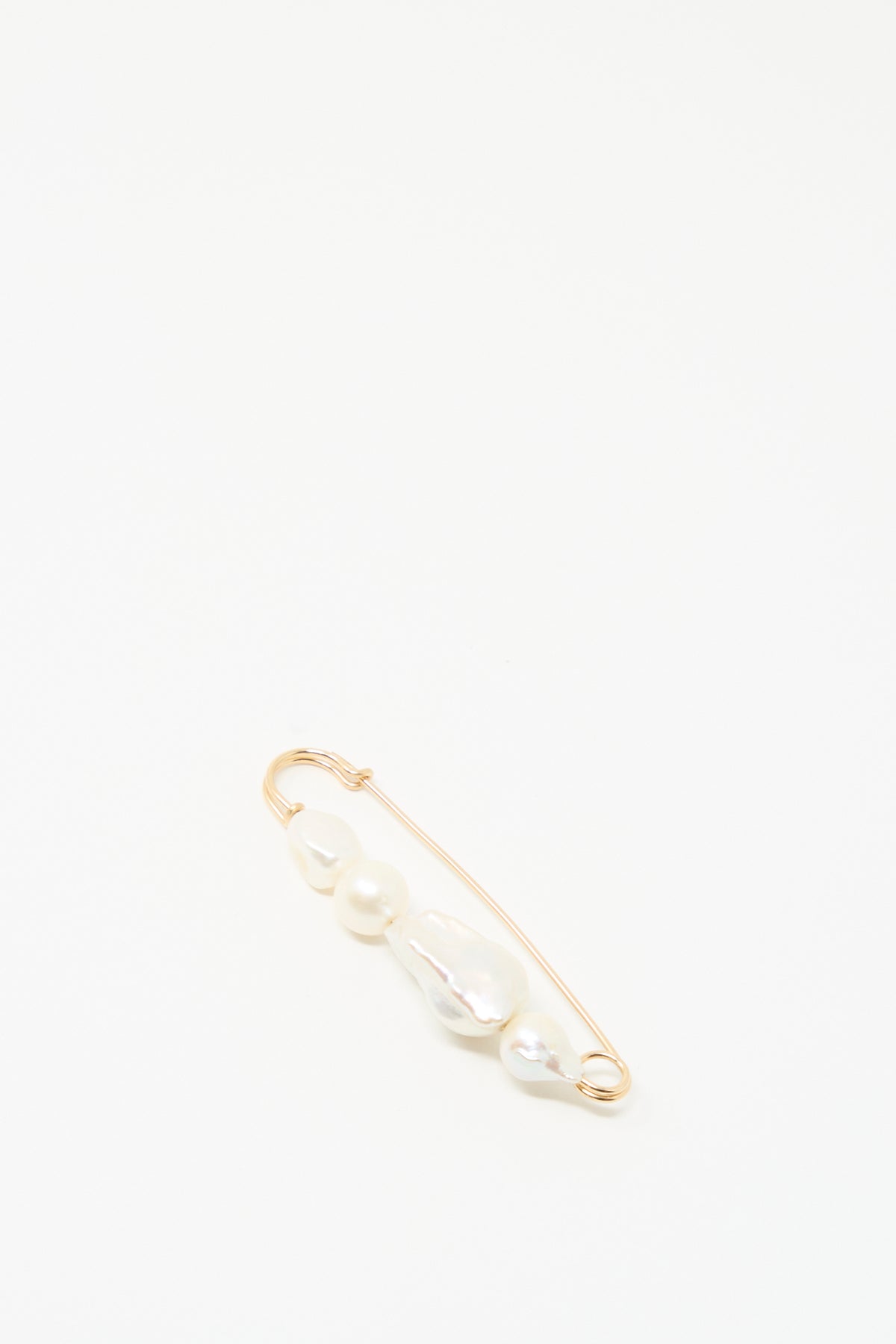 The Quatro Pearl Pin by Mary MacGill features four unique white pearls on a gold-filled safety pin, shown on a simple white background.
