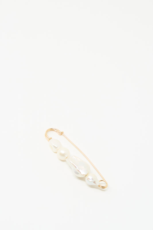 The Quatro Pearl Pin by Mary MacGill features four unique white pearls on a gold-filled safety pin, shown on a simple white background.