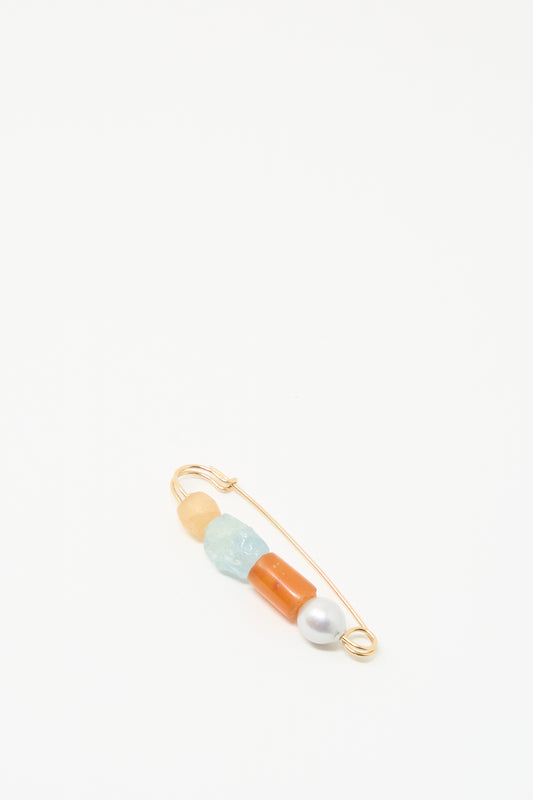 The Rising Summer Pin by Mary MacGill features four beads, including carnelian and a baroque pearl, on a gold-filled safety pin displayed on a white background.