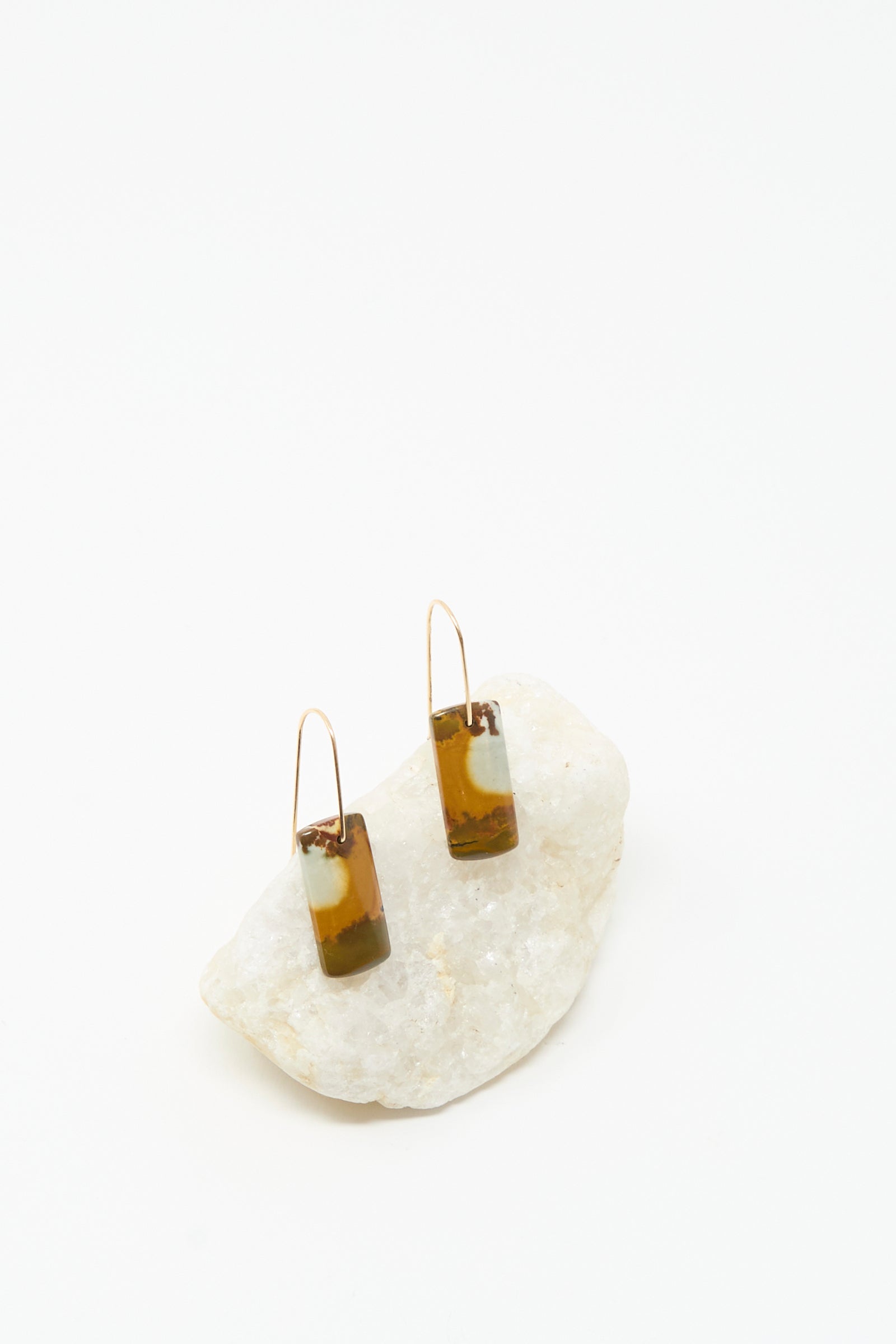 The Stone Drop Earrings in Blue Brown Agate Stone by Mary MacGill feature handmade rectangular agate dangles with 14k gold-filled accents, displayed on a white stone against a white background.