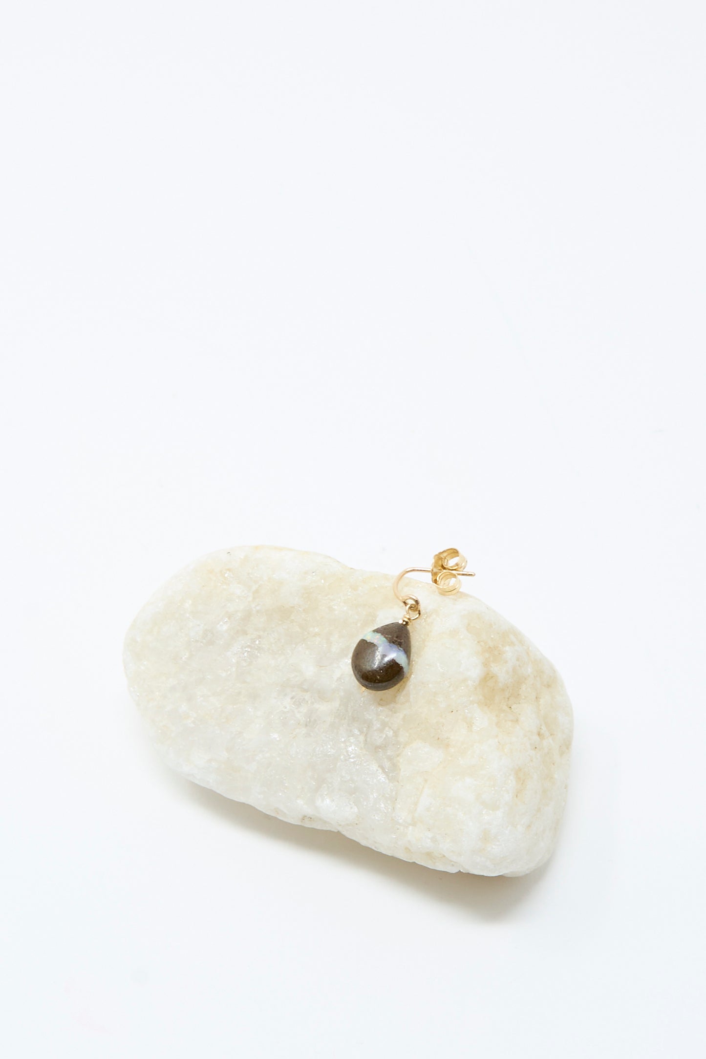 The Mary MacGill 14K Crescent Charm Single Earring in Boulder Opal features elegant 14k gold craftsmanship, displayed as a single handmade piece with a boulder opal pendant on a smooth, light-colored stone against a white background.