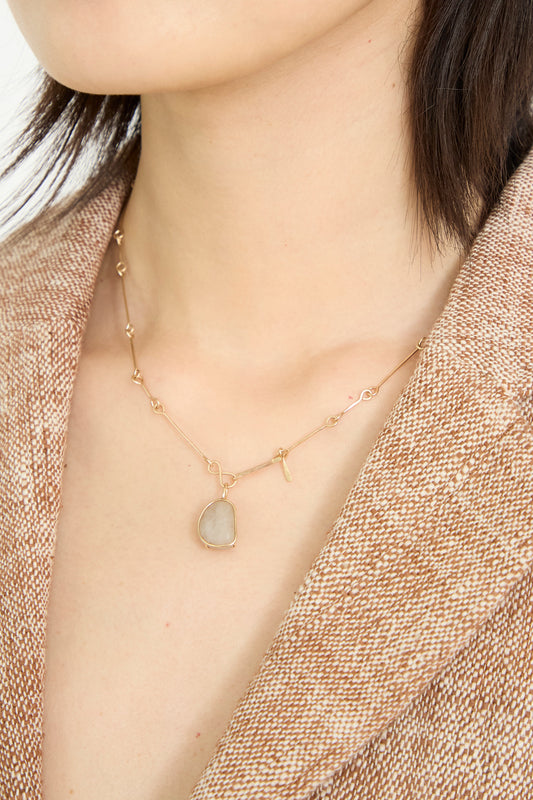A person wearing a Mary MacGill 14K Floating Bone Chain Necklace in Block Island Stone, paired with a textured brown blazer.