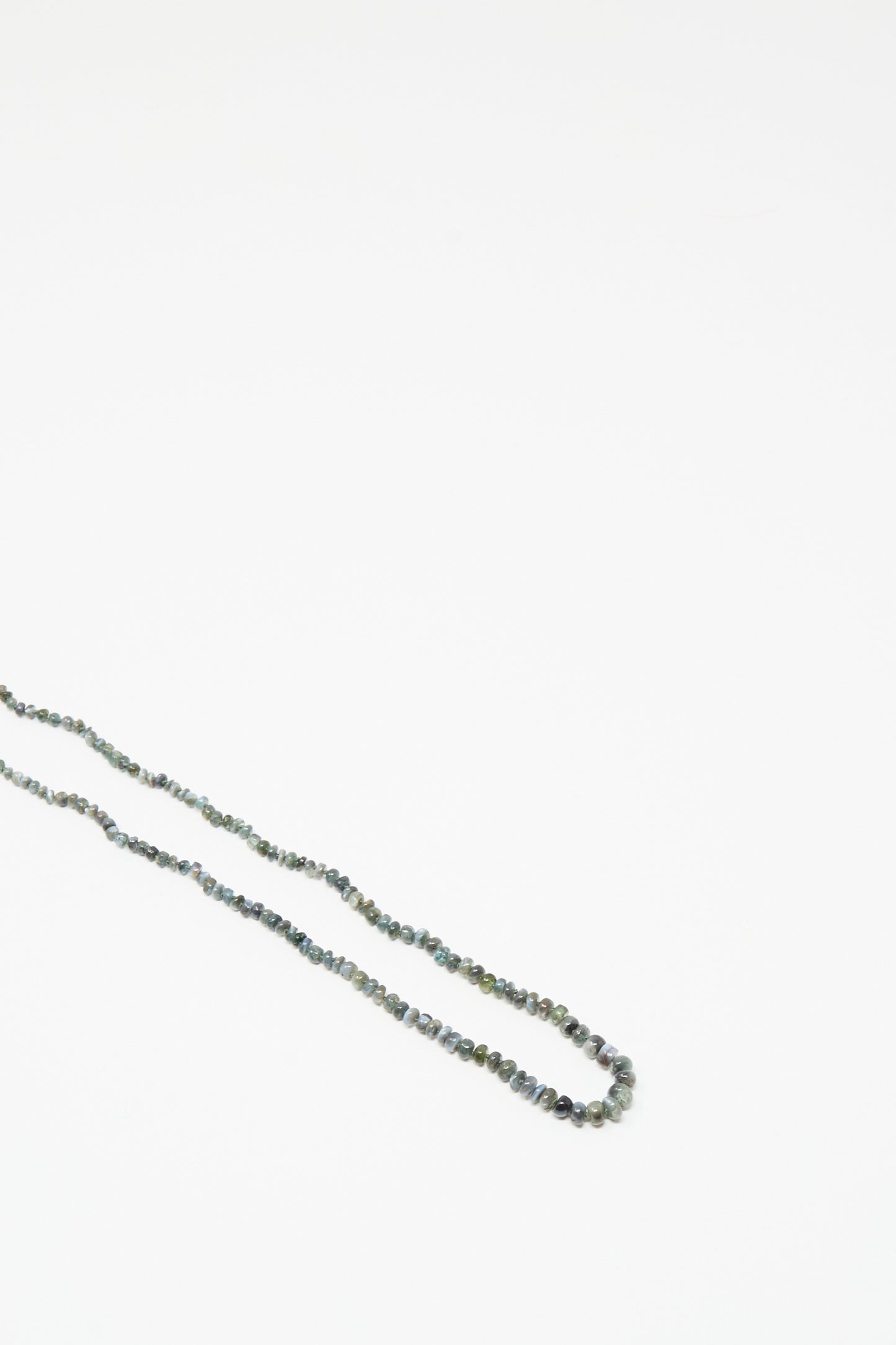 The 14K Stone Layering Necklace in Cat's Eye by Mary MacGill features dark-colored beads on a plain white background, making it a captivating addition to your layering collection.