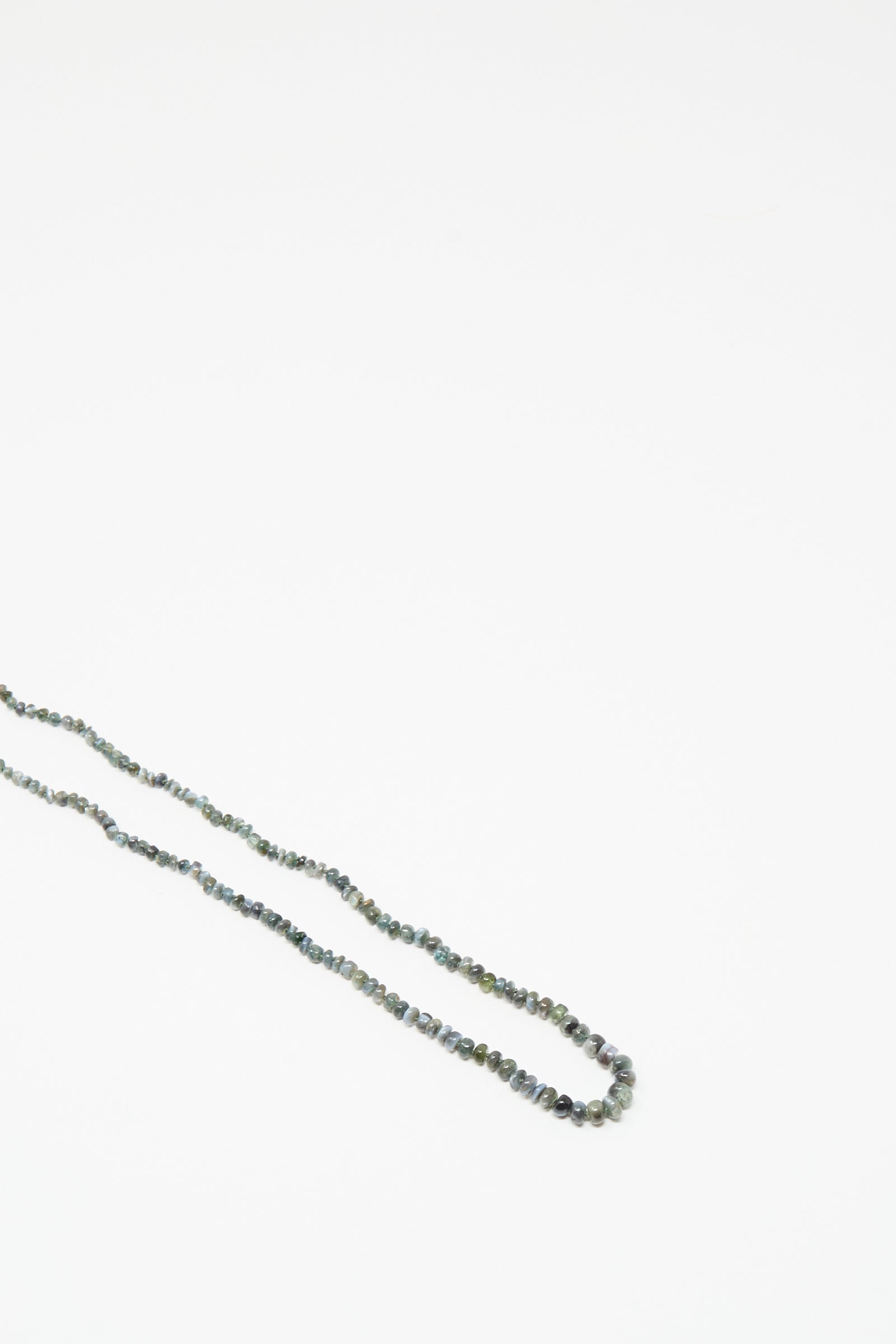 The 14K Stone Layering Necklace in Cat's Eye by Mary MacGill features dark-colored beads on a plain white background, making it a captivating addition to your layering collection.