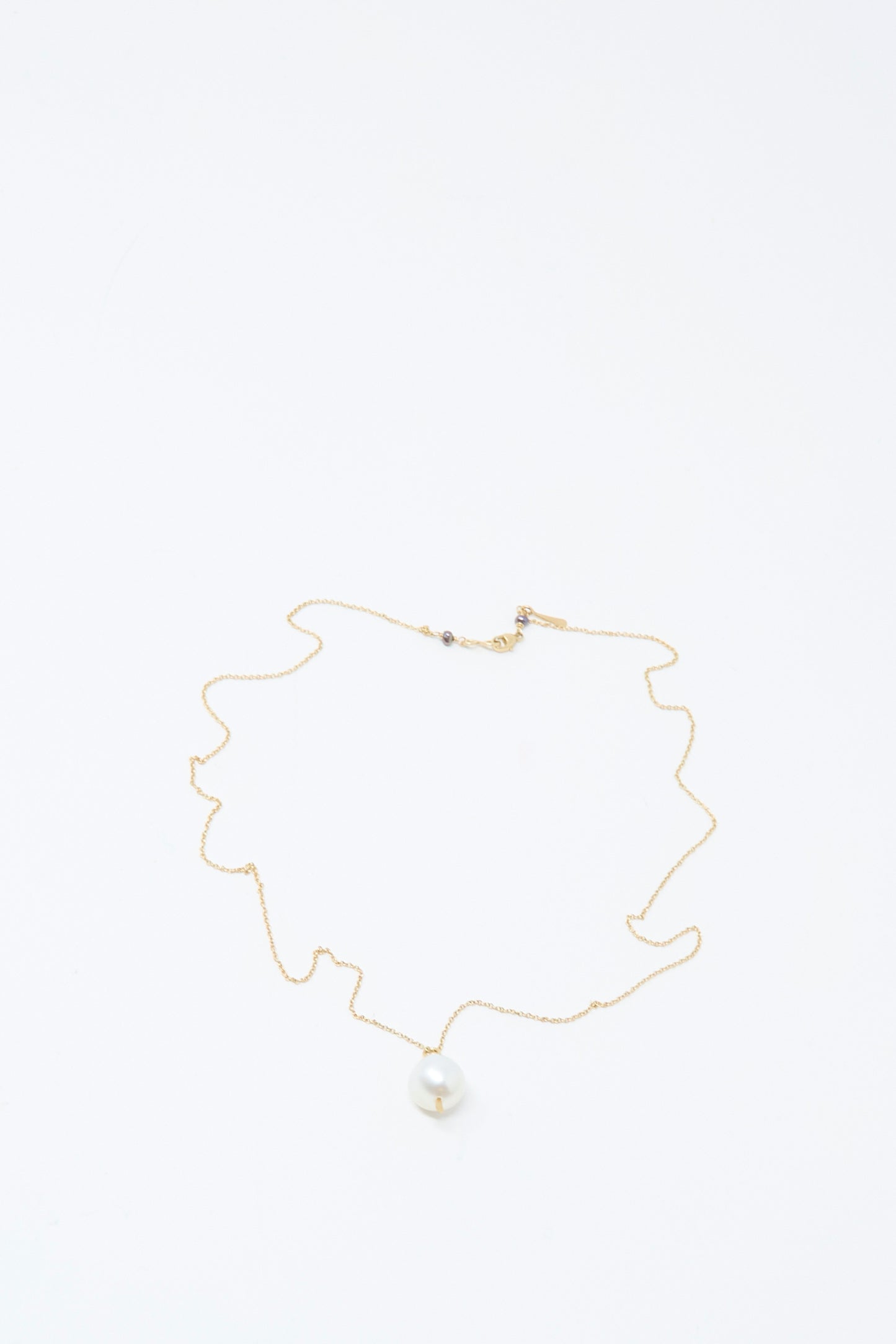 The Mary MacGill 14K Tahitian Pearl Drop Necklace in White is a delicate handmade jewelry piece, featuring a single white pearl pendant on a gold chain, elegantly displayed on a plain white background.