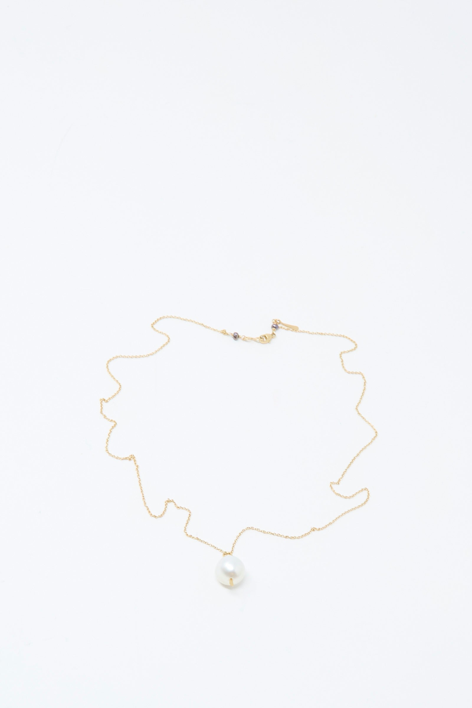 The Mary MacGill 14K Tahitian Pearl Drop Necklace in White is a delicate handmade jewelry piece, featuring a single white pearl pendant on a gold chain, elegantly displayed on a plain white background.