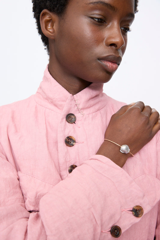 A thin gold Baroque Pearl Cuff featuring a single large, irregular-shaped baroque pearl worn on a person’s wrist.