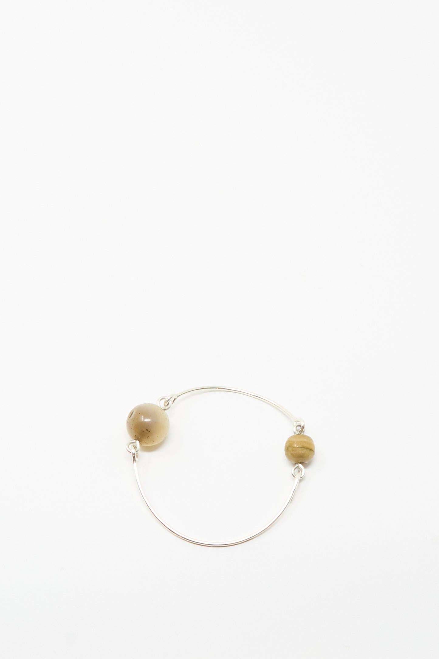 The Mary MacGill Hammered Sterling Silver Bangle with Ancient Agate Trade Beads features two spaced agate beads on a slim silver band—a unique piece of handmade jewelry, shown against a plain white background.