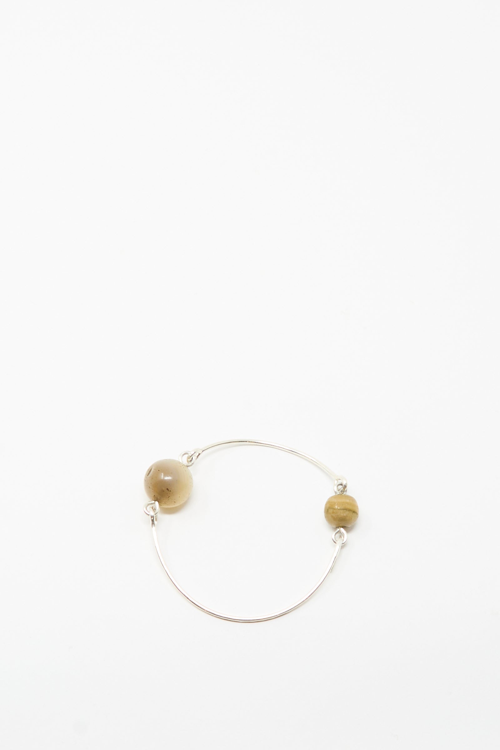 The Mary MacGill Hammered Sterling Silver Bangle with Ancient Agate Trade Beads features two spaced agate beads on a slim silver band—a unique piece of handmade jewelry, shown against a plain white background.