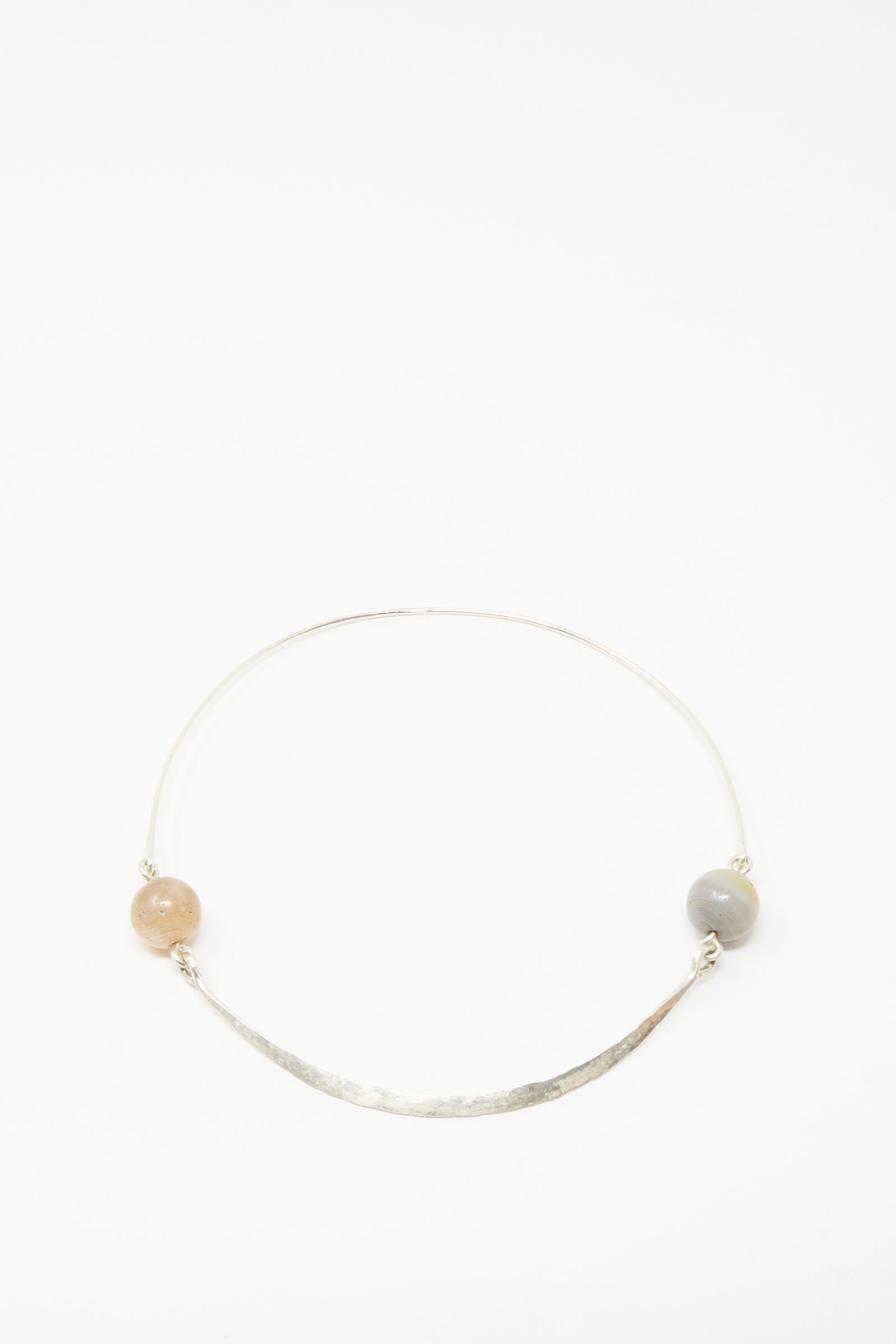 The Mary MacGill Hammered Sterling Silver Collar features ancient agate trade beads—one light brown, one gray—on a sleek, minimalist bar, displayed on a plain white background. A timeless piece of handmade jewelry.