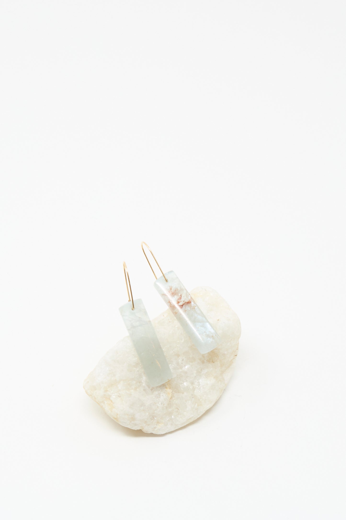 Rectangular, translucent Blue Calcite Stone Drop Earrings by Mary MacGill with 14k gold-filled hooks, shown on a white stone against a plain white background.