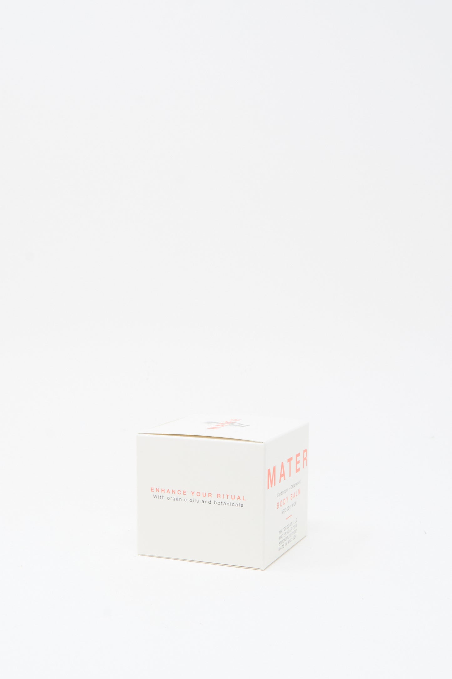 A white box labeled "Mater Soap" with text "Enhance your ritual with organic oils and botanicals" sits on a plain white background, perfect for those seeking botanical skincare or the Cardamom and Cedarwood Body Balm 3oz.