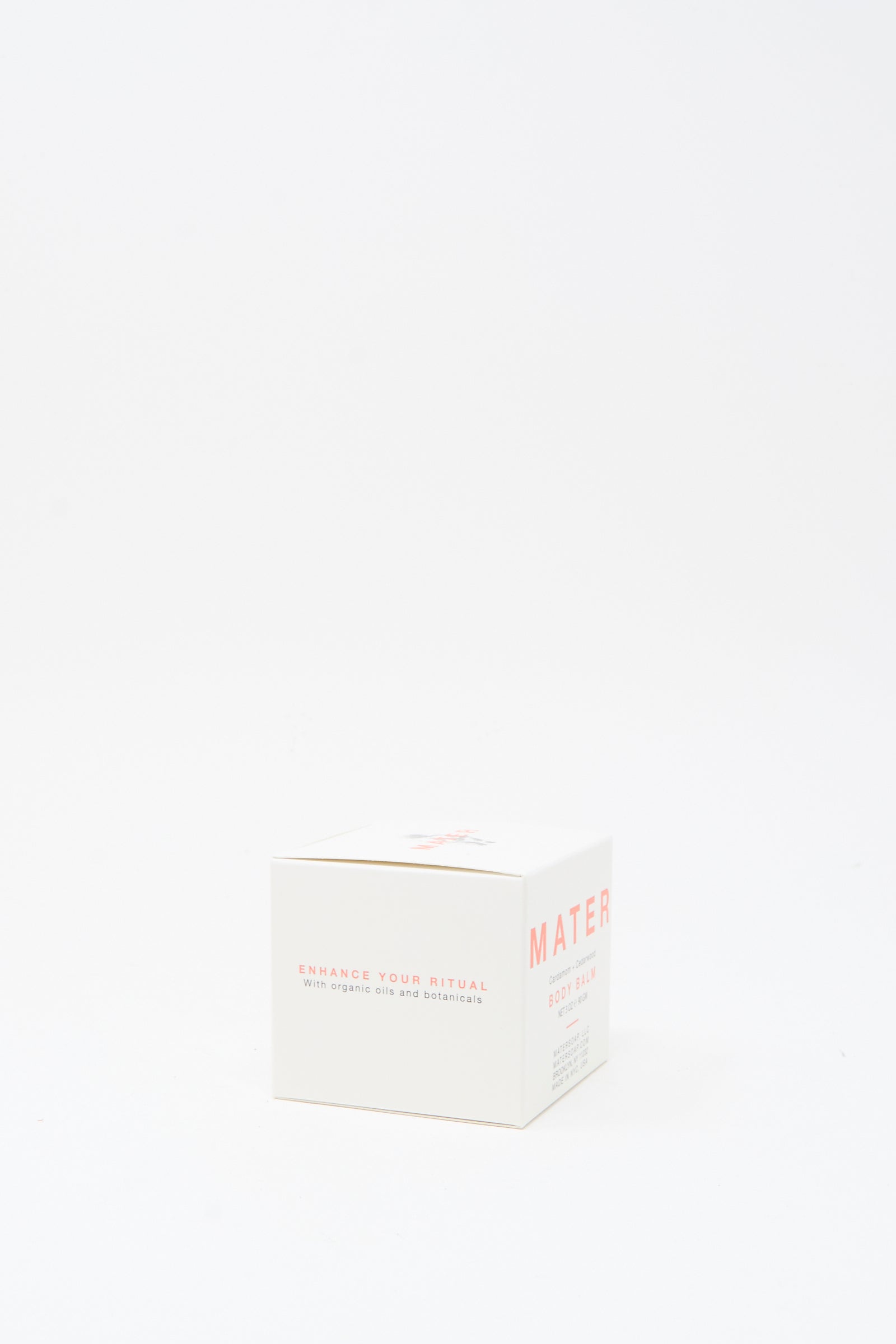 A white box labeled "Mater Soap" with text "Enhance your ritual with organic oils and botanicals" sits on a plain white background, perfect for those seeking botanical skincare or the Cardamom and Cedarwood Body Balm 3oz.