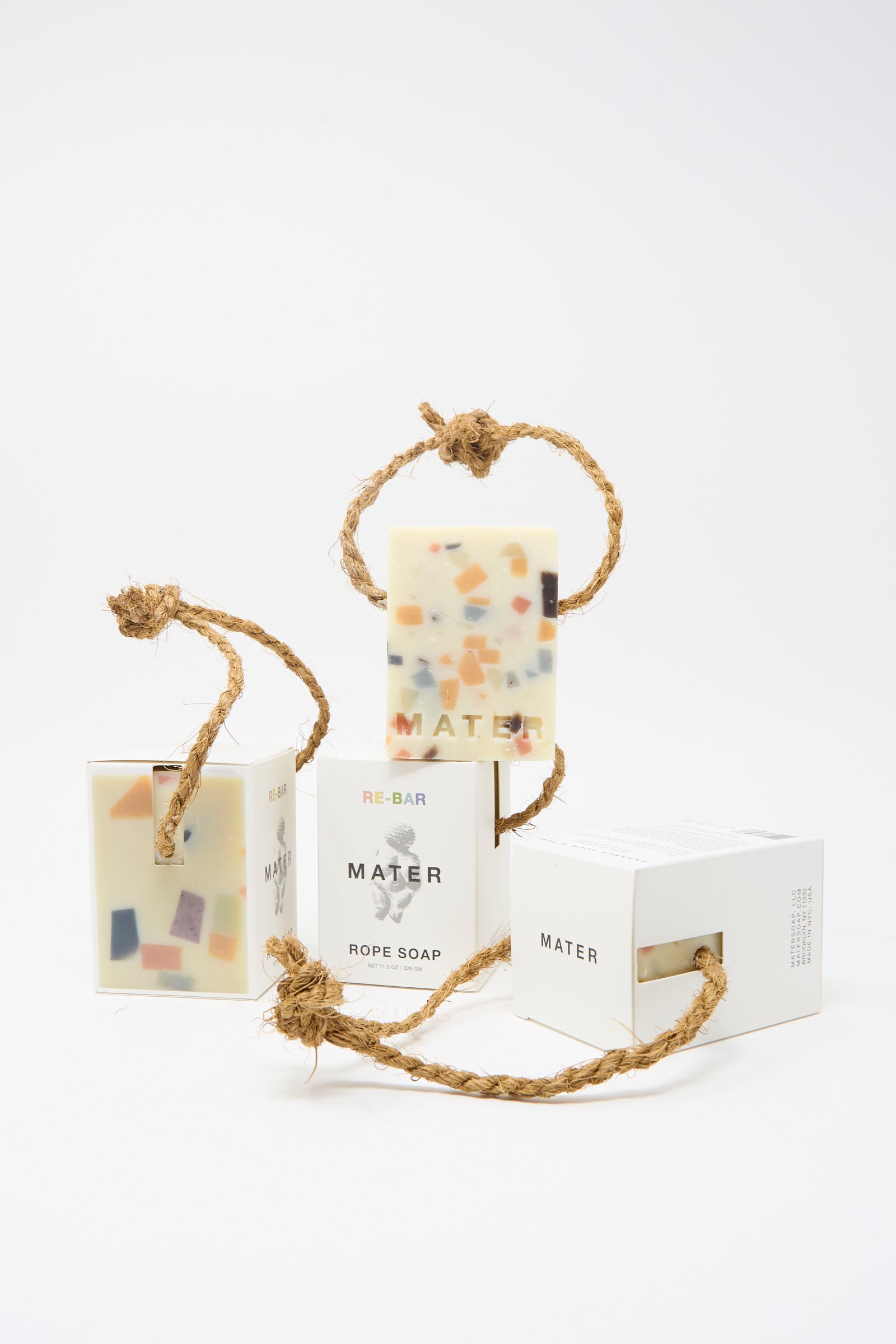 Three Re-Bar Rope Soap bars by Mater Soap, each olive-based with colorful terrazzo pieces and a sturdy twisted rope, are shown alongside their packaging.