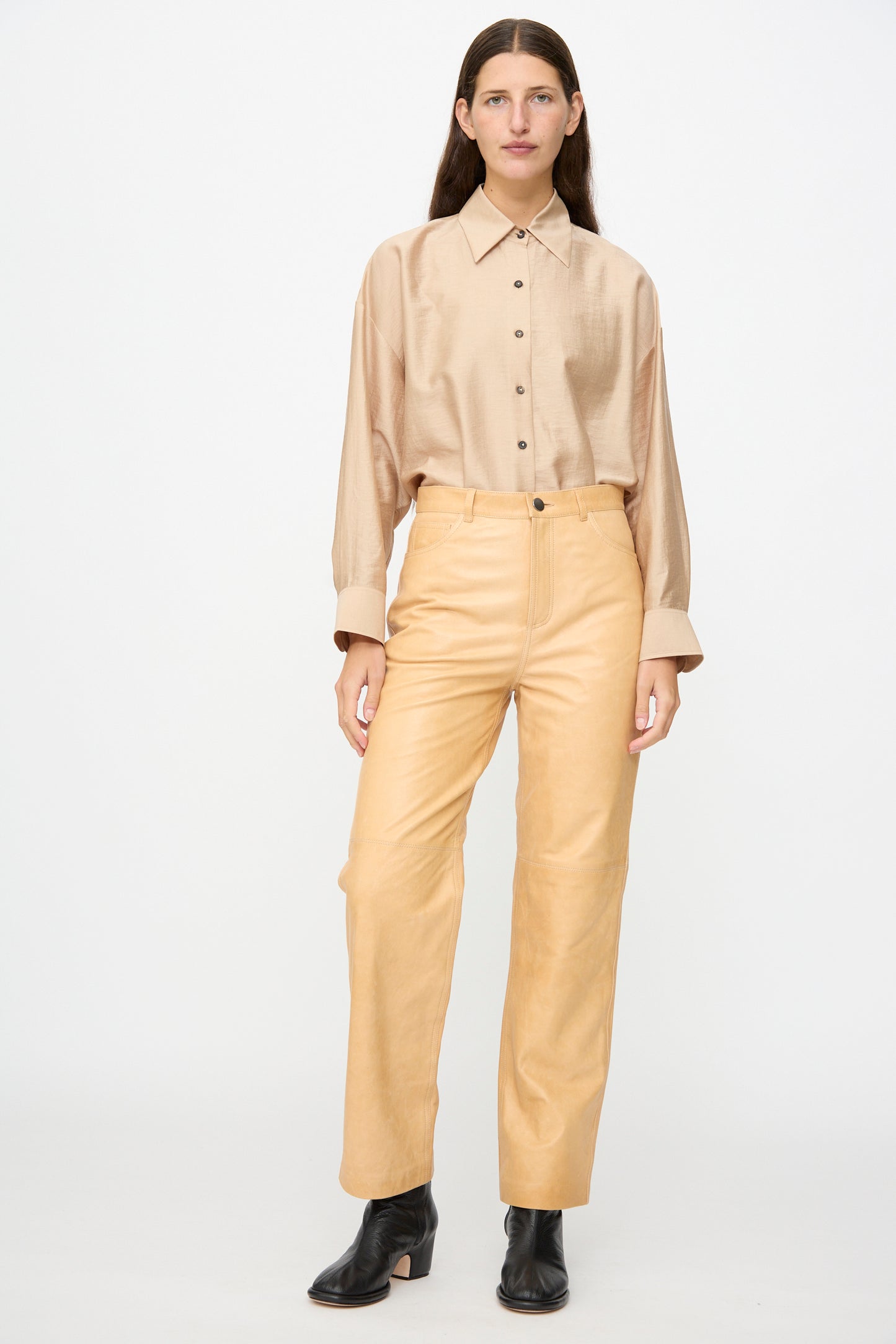 A person stands against a plain backdrop wearing the Milena Silvano Leather 5 Pocket Trousers in Bare.