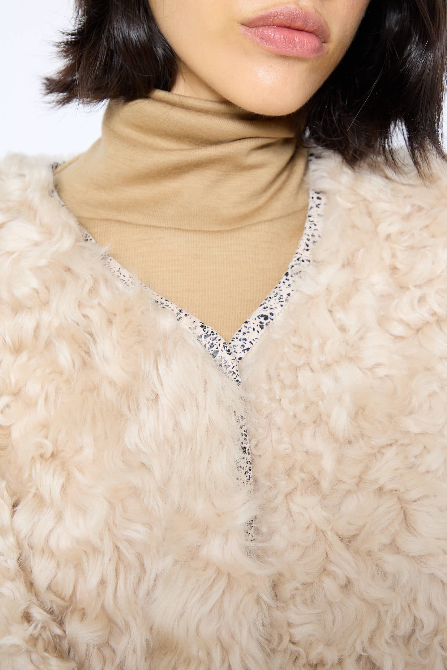 Close-up of a person wearing Milena Silvano's Pyramid Robe in Classic, layered over a beige turtleneck. The person has short, dark hair.