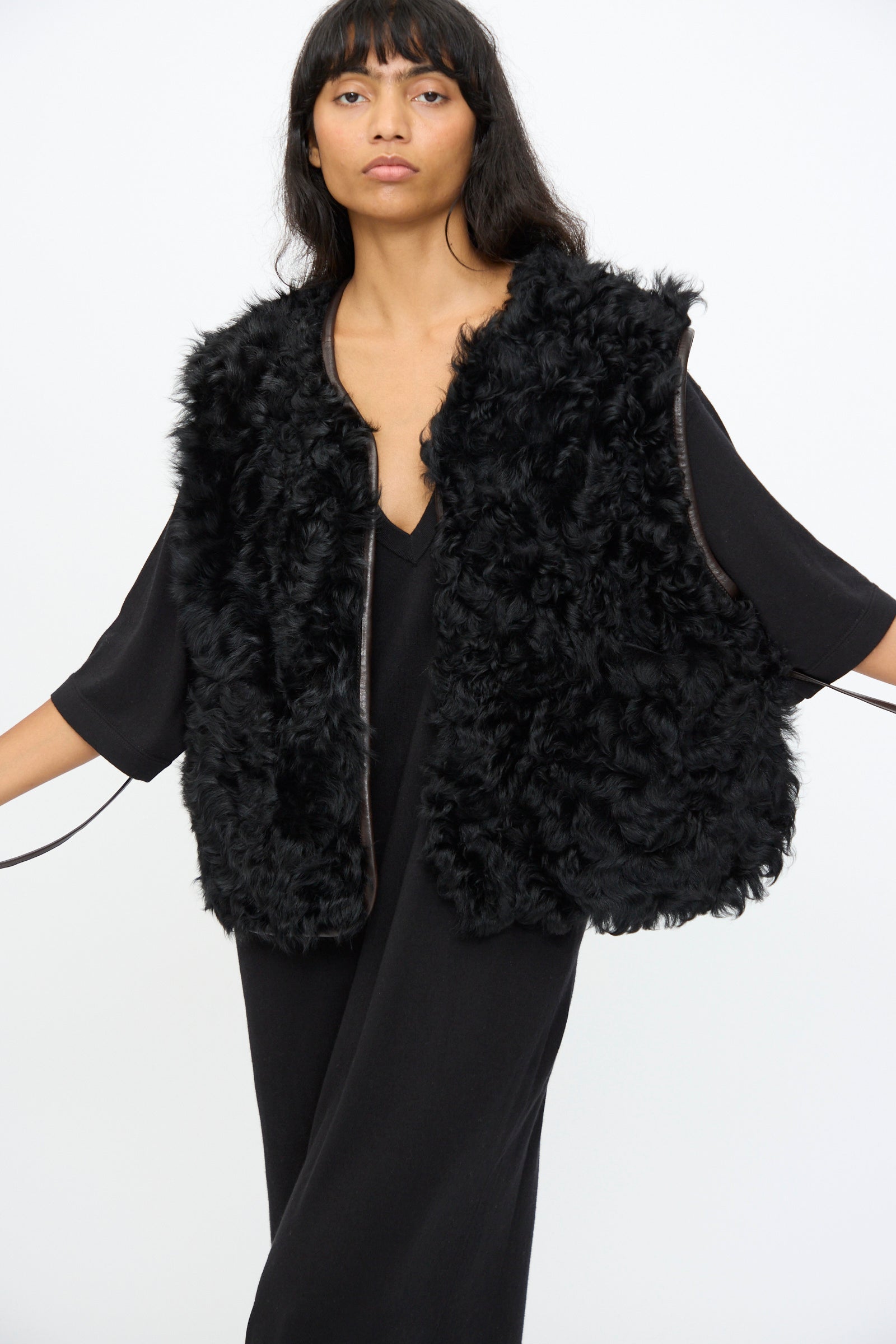 A woman wears Milena Silvano's Transition Vest in Chaga over a loose black dress, standing against a plain white background.