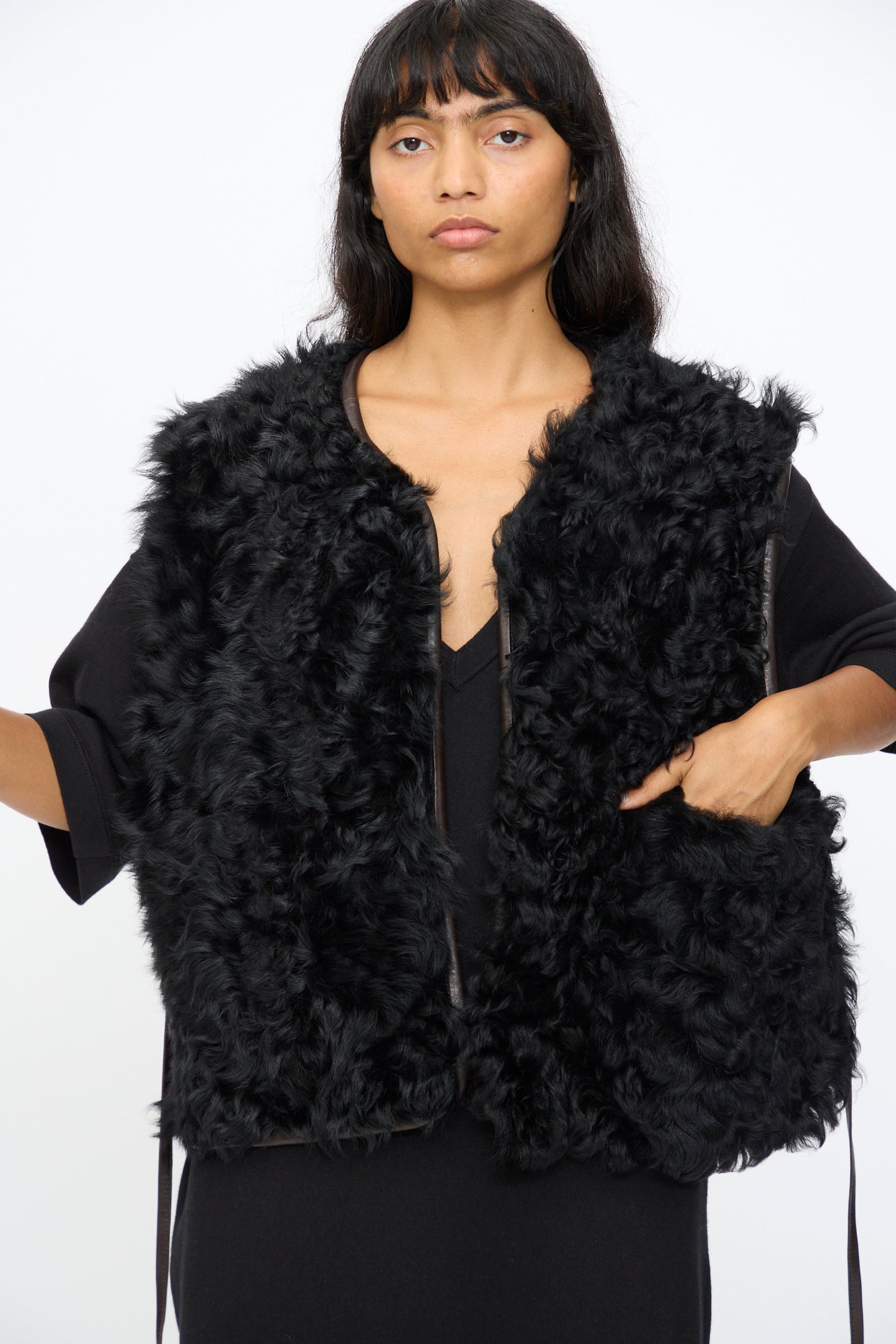 A person wears the Milena Silvano Transition Vest in Chaga over a black dress, standing against a plain white background.