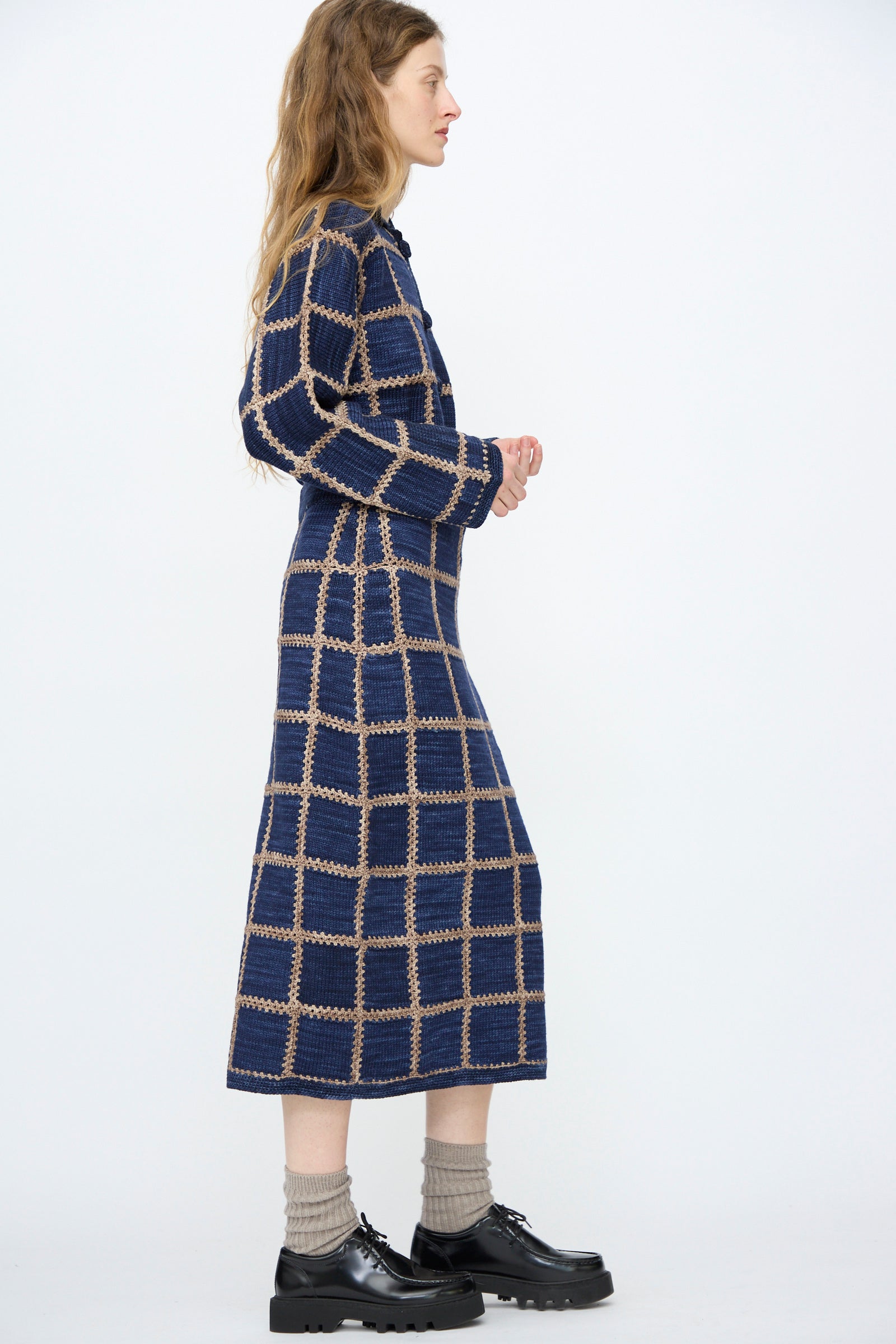 A woman stands in profile against a white background, wearing the Misha & Puff Ladder Square Skirt in Ink, paired with light gray socks and black platform shoes.