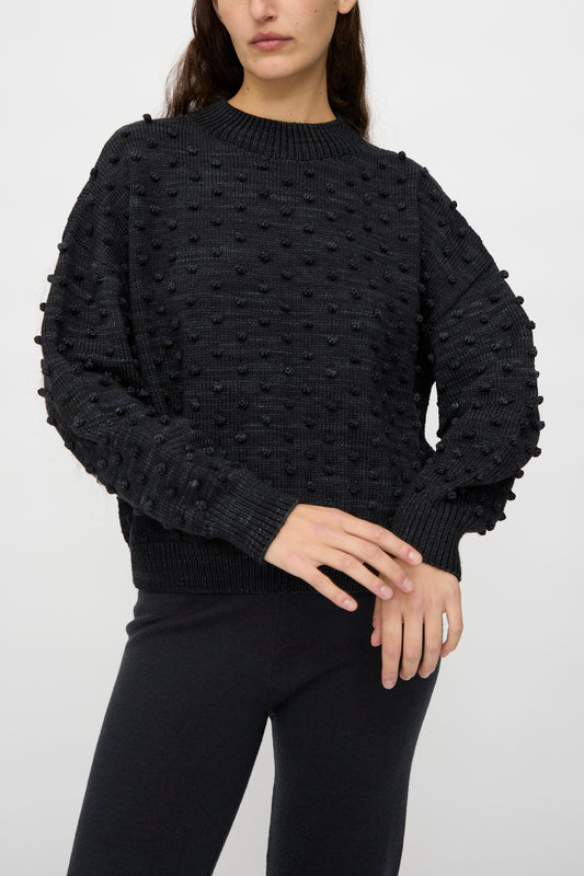 A person wears the Original Popcorn Sweater in Carbon by Misha & Puff with black pants, standing against a plain white background.