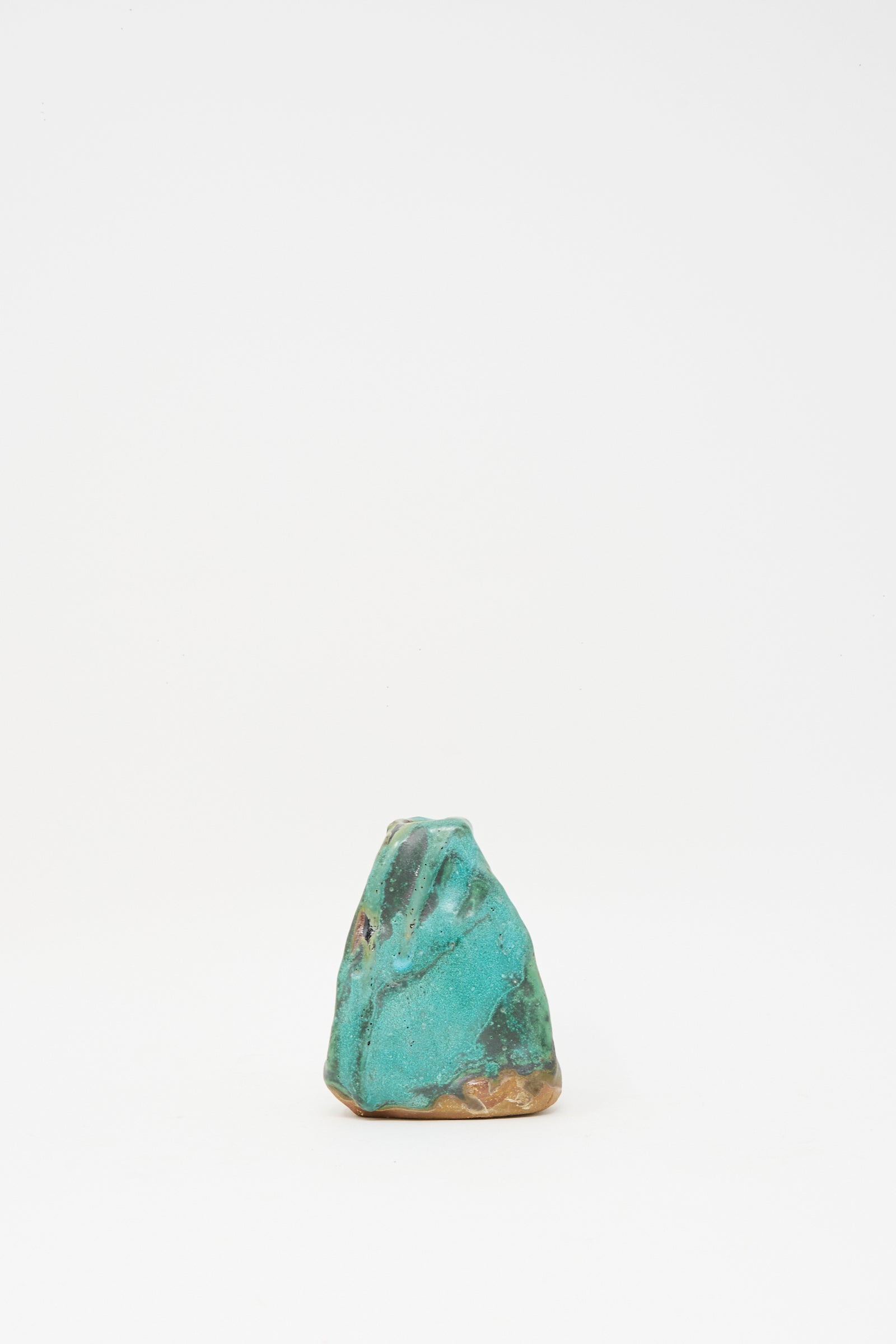 The Carved Bud Vase III by MONDAYS, a small, uniquely shaped turquoise and brown clay piece, is displayed centered on a plain white background.