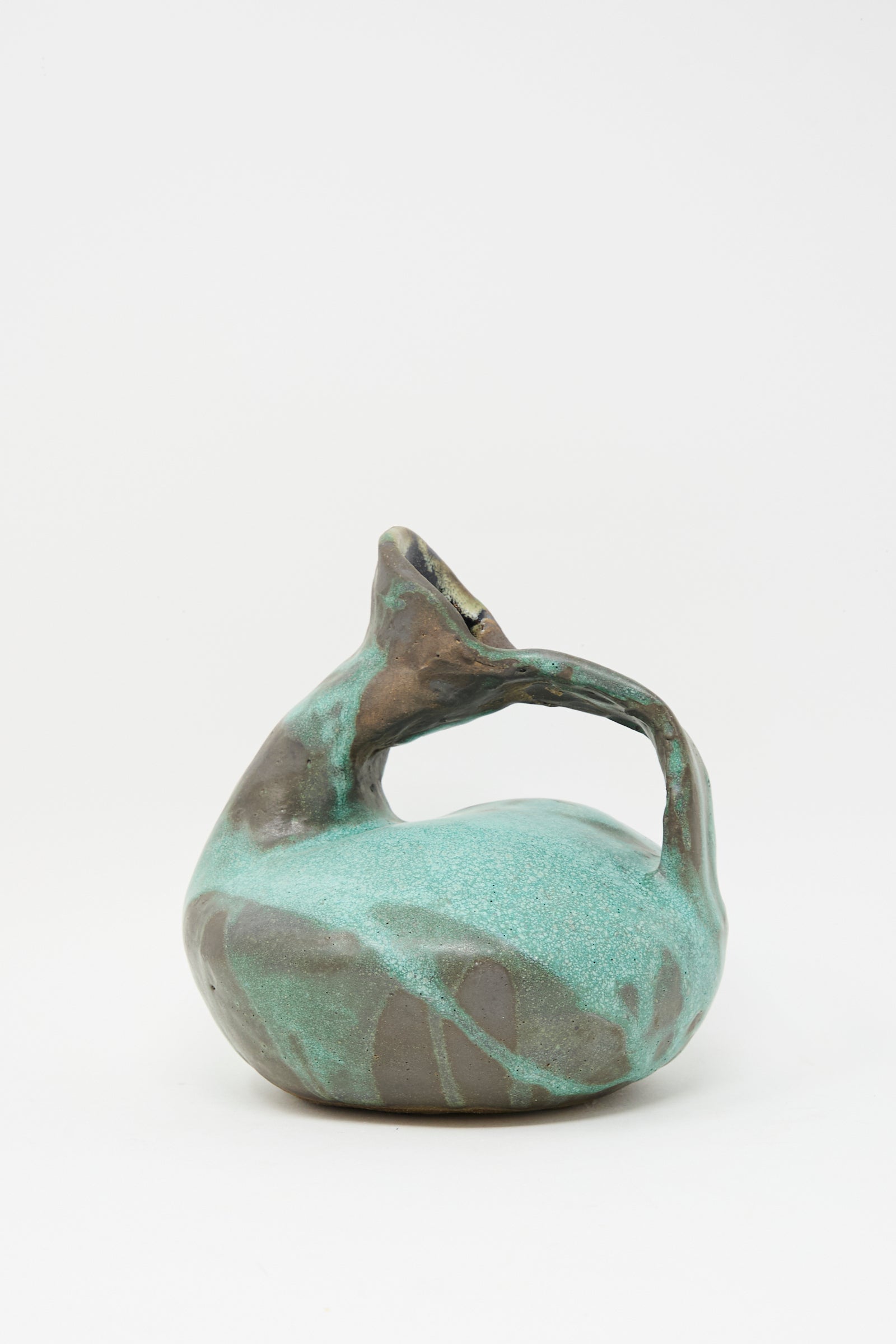 The MONDAYS Glazed Stoneware Pitcher Vase in Green features a hand-built design with a rounded base, twisted handle, and spout. It’s finished with turquoise, green, and brown glazes and displayed on a plain white background.