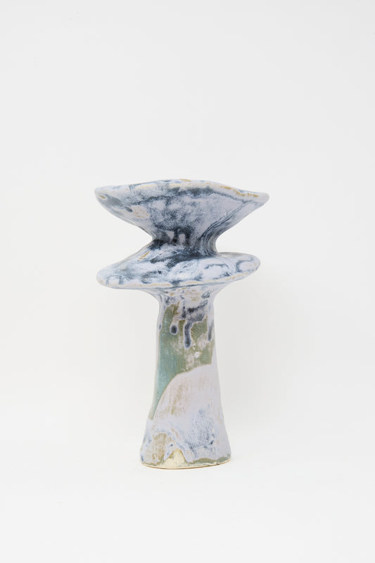 The MONDAYS Glazed Stoneware Vase in Blue features a sculptural design with a tall, narrow base, two flared, layered tops, and blue, white, and beige marbled glazing with a striking blue effect.