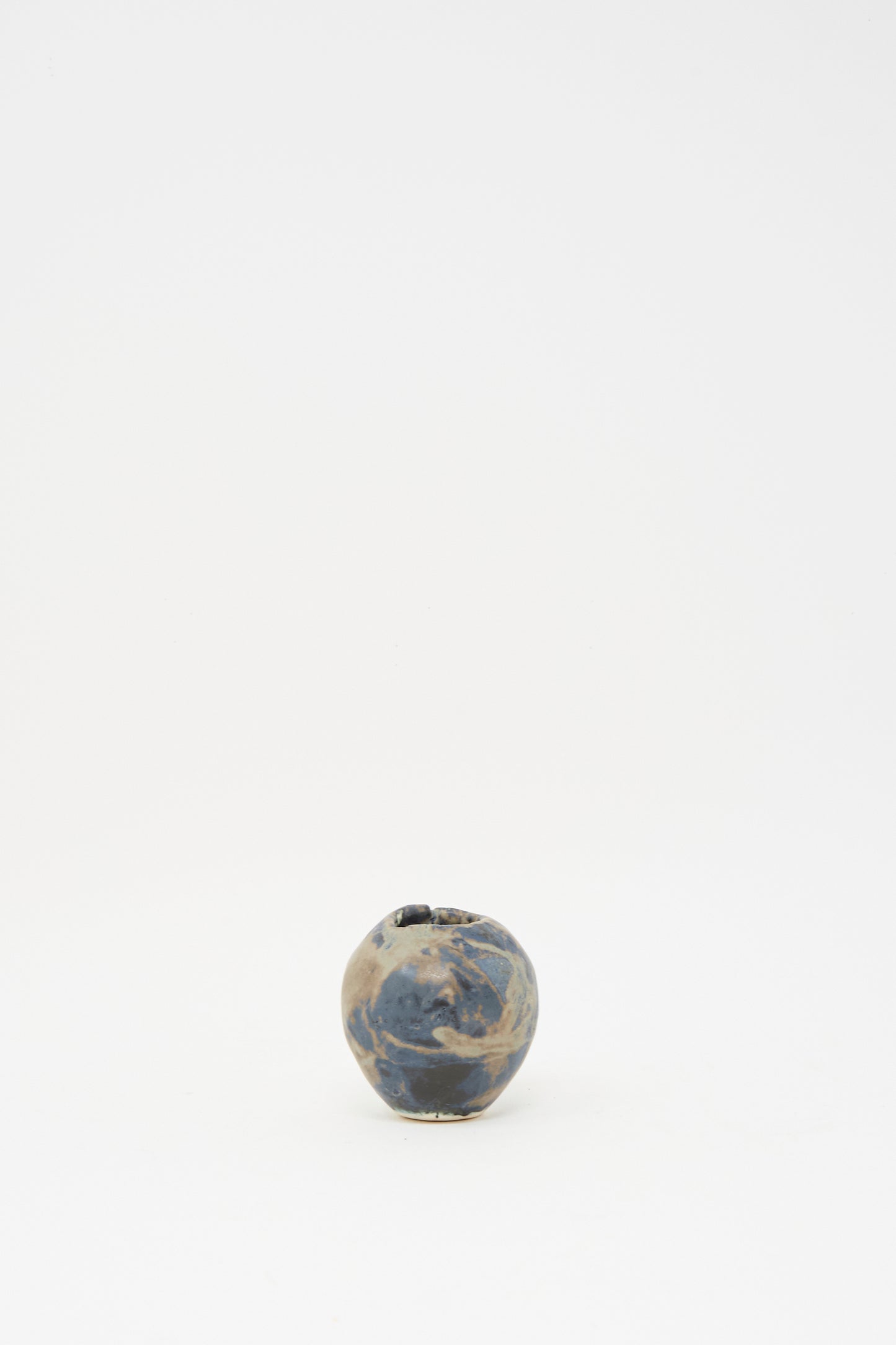 The MONDAYS Mini Bud Vase I, hand-built in porcelain with a marbled blue and beige glaze, is displayed centered on a plain white background.